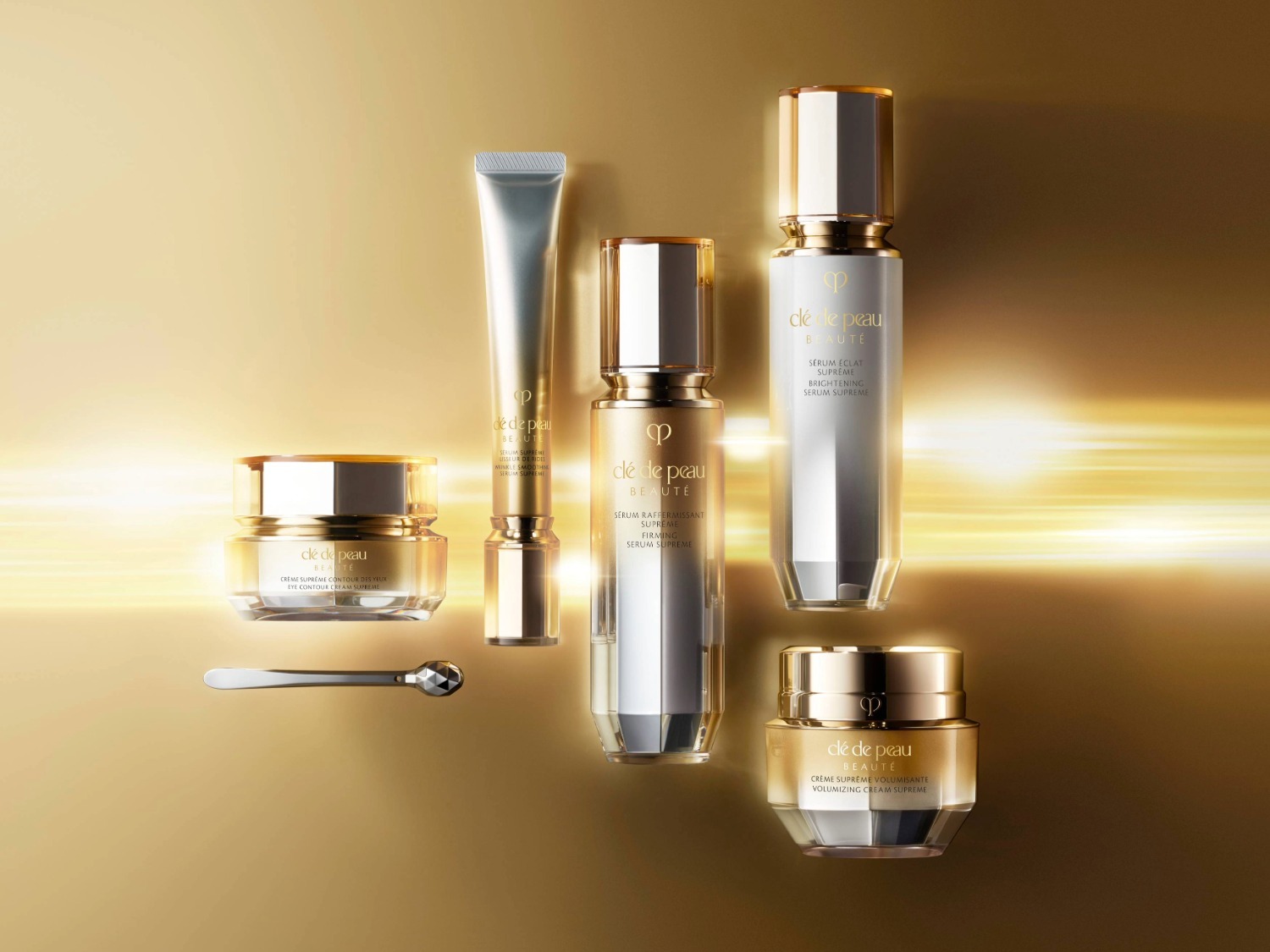 Découvrez une collection de soins de la peau Clé de Peau Beauté, comprenant des crèmes pour les yeux et des sérums raffermissants et éclaircissants, présentés dans des emballages élégants or et argent.