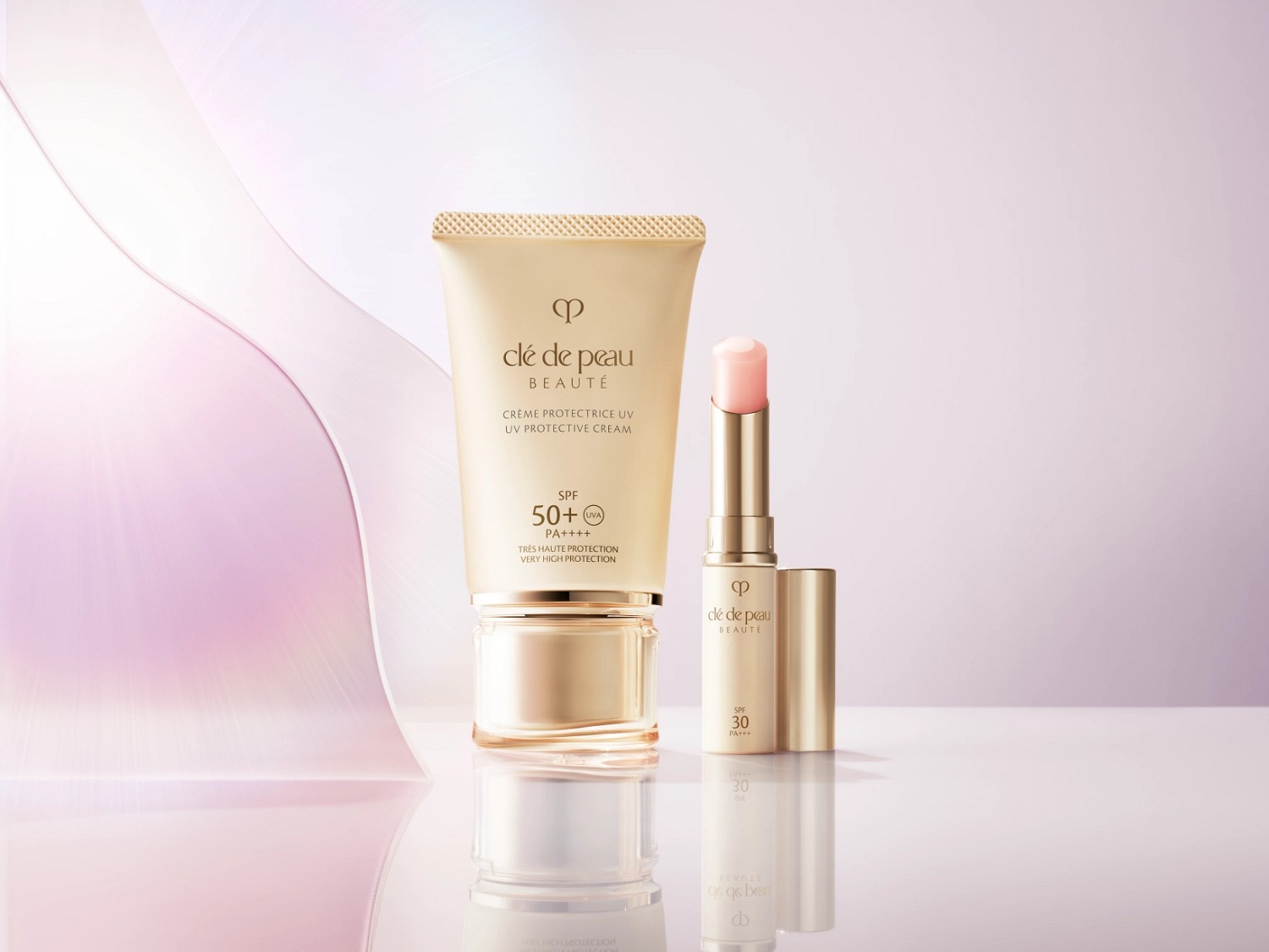 Voici la Crème Protectrice UV SPF 50+ de Clé de Peau Beauté dans un tube doré, et un baume à lèvres SPF 30 dans un élégant emballage doré.