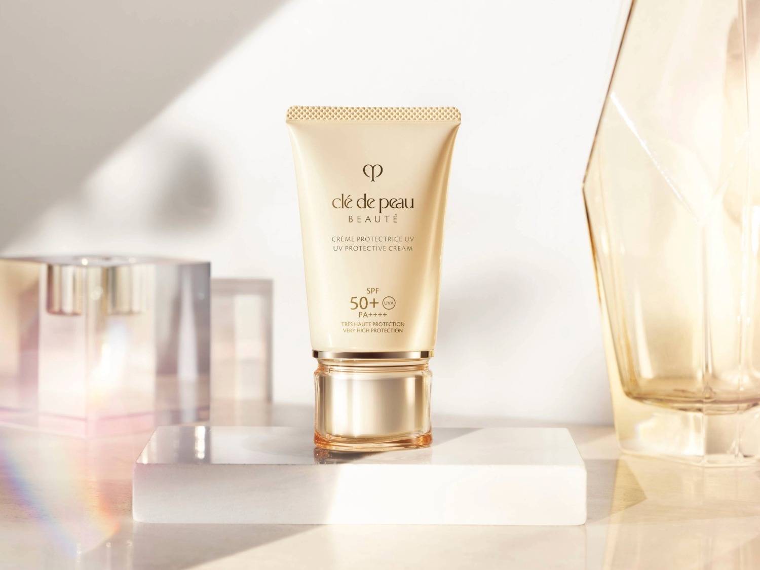 Voici un tube de crème solaire Clé de Peau Beauté, offrant une très haute protection SPF 50+ PA++++ contre les rayons UV, le tout dans un emballage élégant.