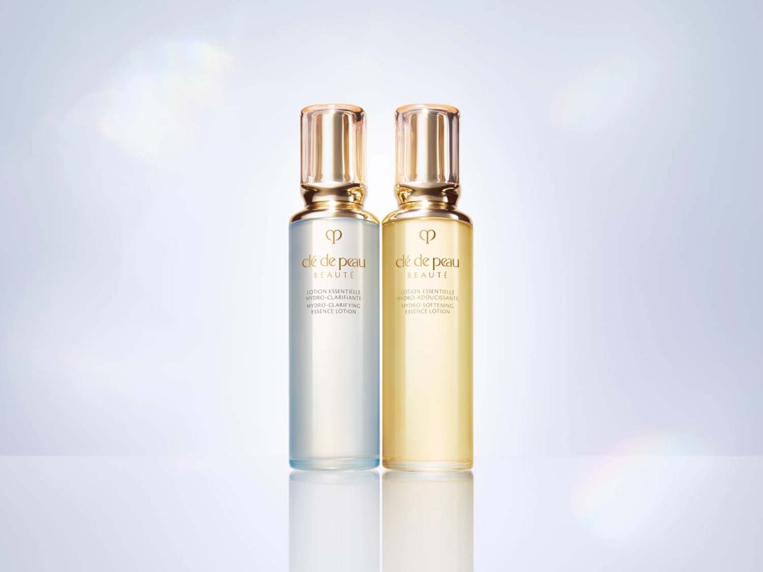 Voici deux lotions essentielles de Clé de Peau Beauté : l'une hydro-clarifiante dans un flacon bleu clair, l'autre hydro-adoucissante dans un flacon jaune clair, toutes deux avec des bouchons dorés.