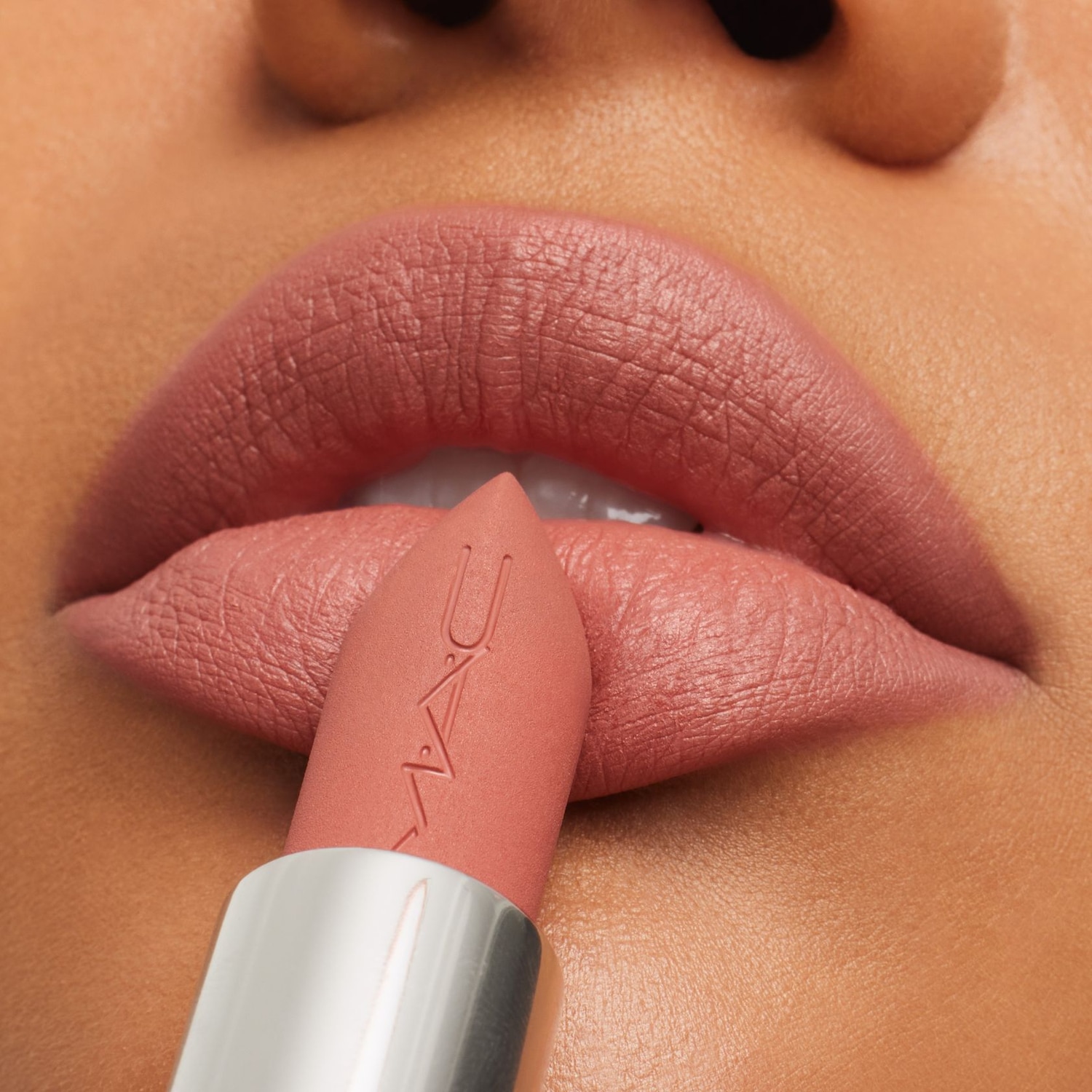 Close-up van een vrouw die MAC-lippenstift aanbrengt, de lippenstift heeft een zilveren huls en een roze kleur.