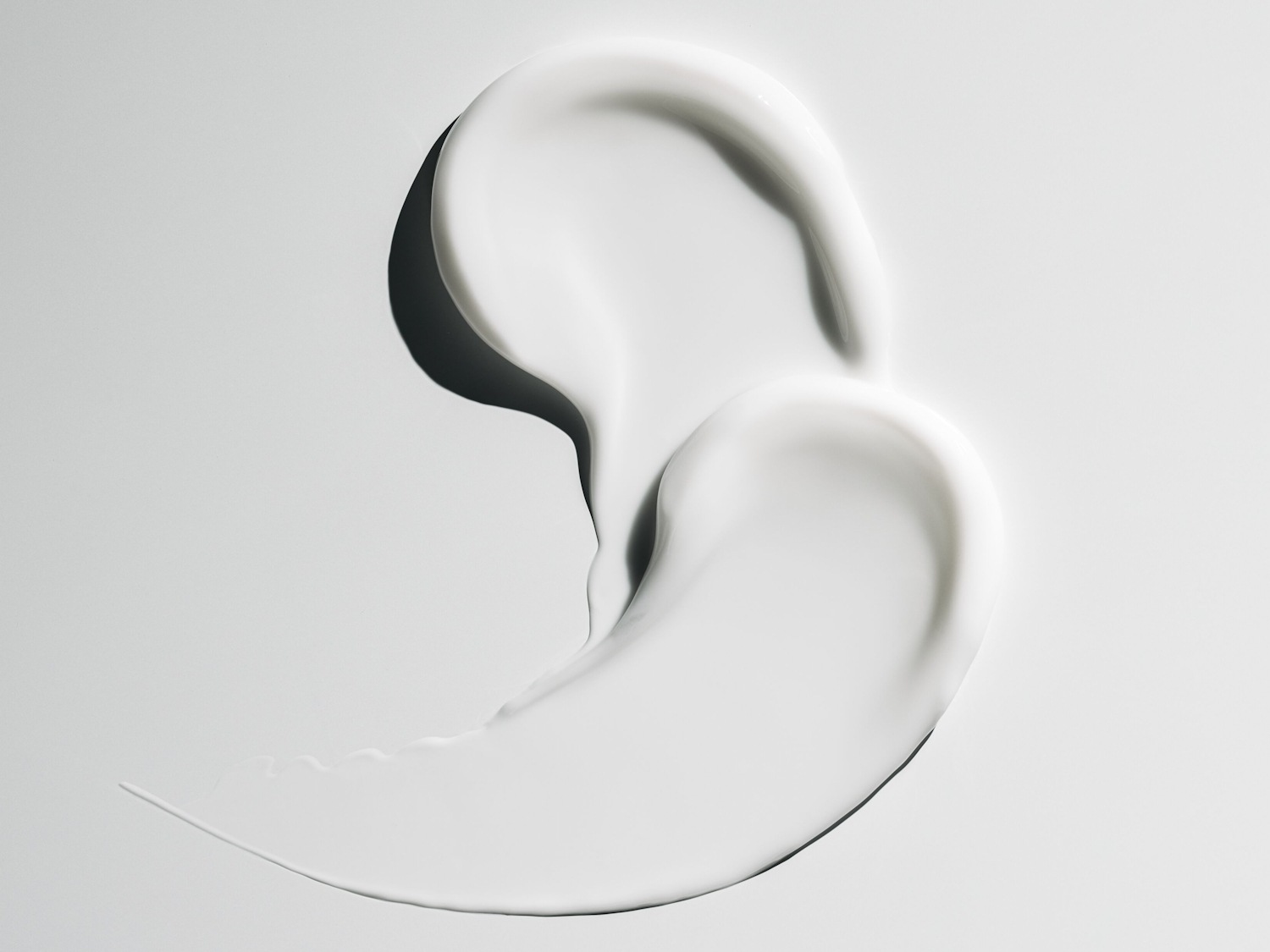 Aquí se muestra una muestra de crema blanca y brillante, extendida sobre una superficie clara, destacando su textura suave y rica.