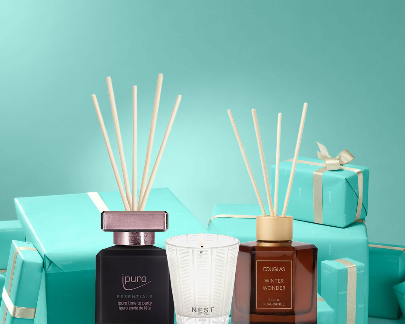 Entdecke die Duftkollektion mit ipuro Essentials Raumduft, Nest Duftkerze und Douglas Winter Wonder Raumduft vor dem Hintergrund von blaugrünen Geschenken.