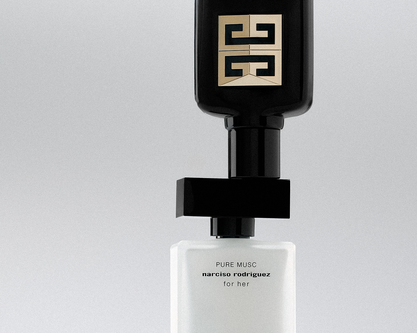 Nahaufnahme von zwei Parfümflaschen, eine schwarze von Givenchy mit goldenem Logo und eine weiße von Narciso Rodriguez mit der Aufschrift „Pure Musc for her“.