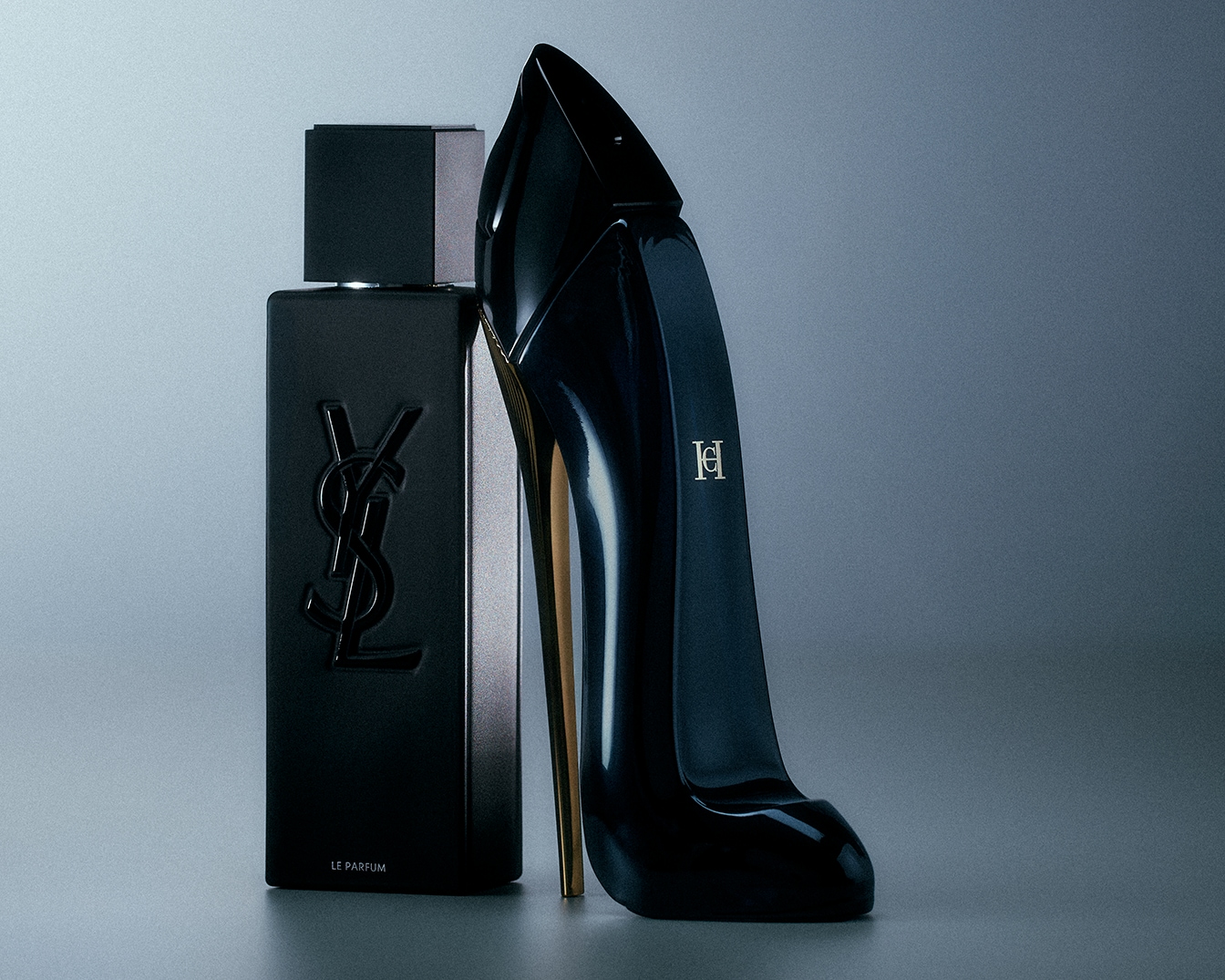 Ein schwarzer YSL-Duft und ein Carolina Herrera-Duft in Form eines hochhackigen Schuhs stehen auf einem grauen Hintergrund.