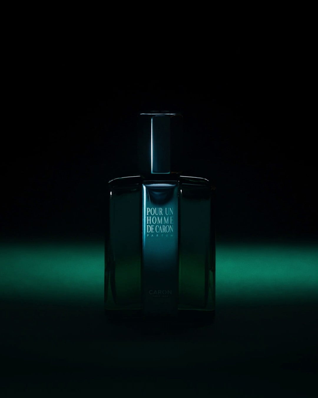 Butelka perfum Caron Pour Un Homme de Caron o pojemności 125 ml ma elegancki, prostokątny kształt i jest wypełniona zielonkawym płynem.