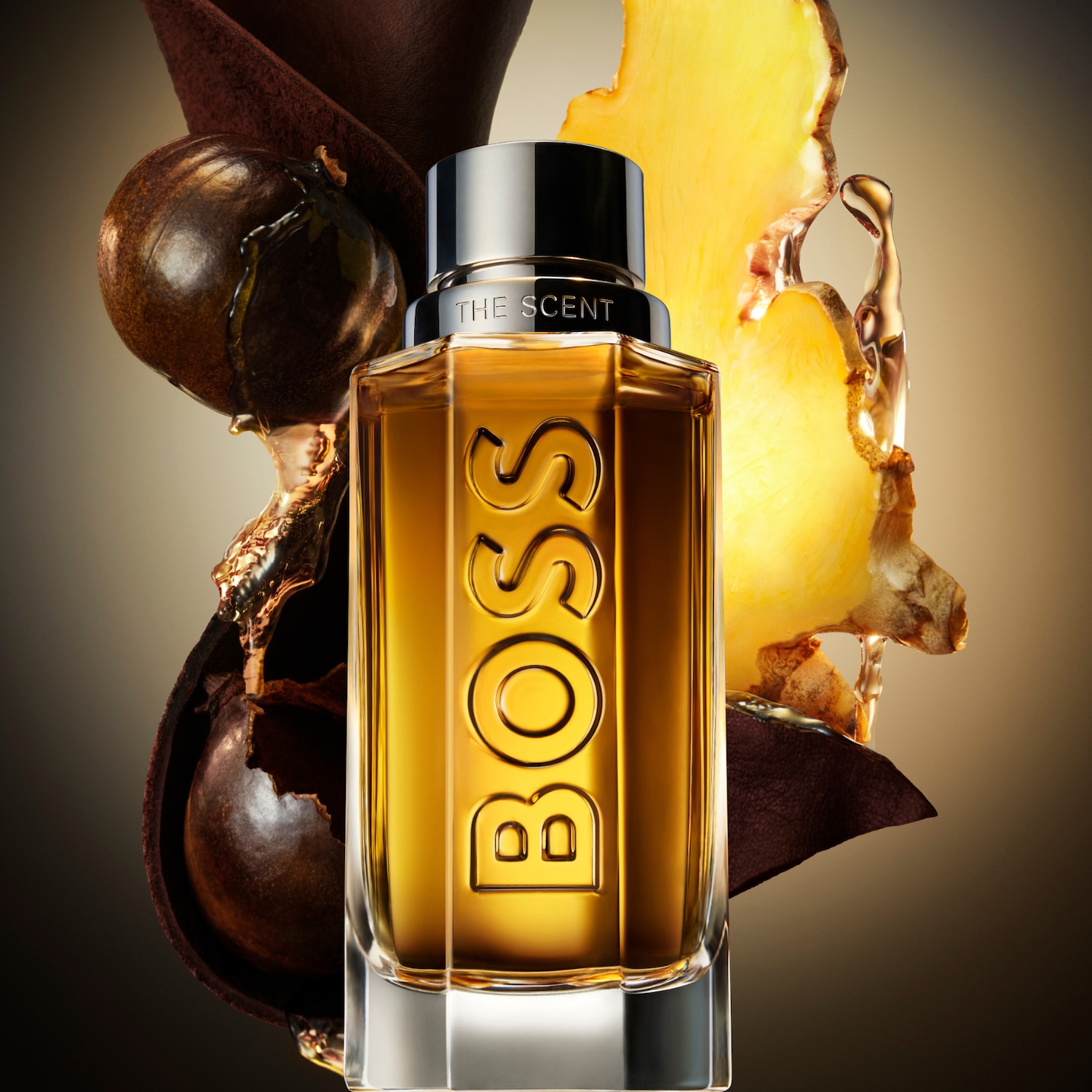 Butelka perfum BOSS The Scent z nutami imbiru i owoców maninka, otoczona brązową tkaniną i kroplami płynu.