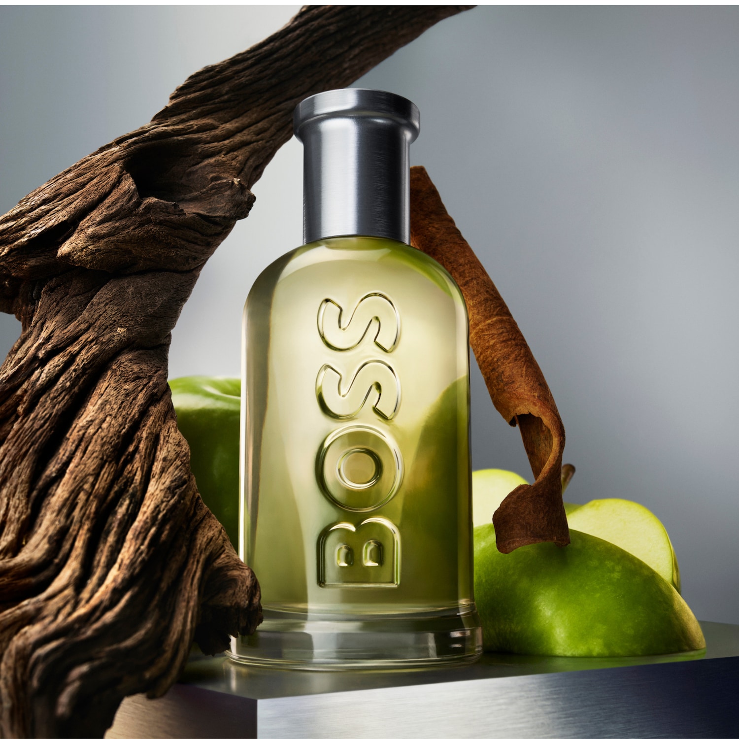 Butelka perfum BOSS z zielonym jabłkiem, korą cynamonu i kawałkiem drewna, tworząca naturalną i świeżą kompozycję zapachową.