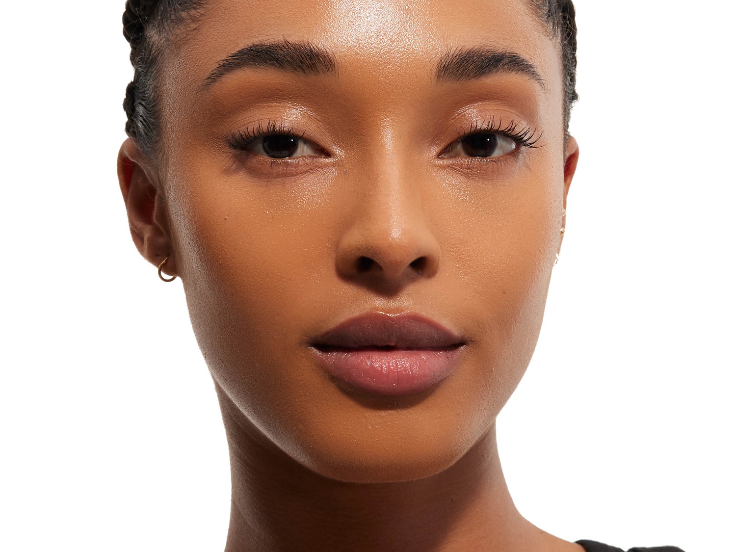 Gros plan sur le visage d'une femme à la peau bronzée, mettant en valeur son teint uniforme, ses sourcils bien définis et ses lèvres légèrement brillantes.