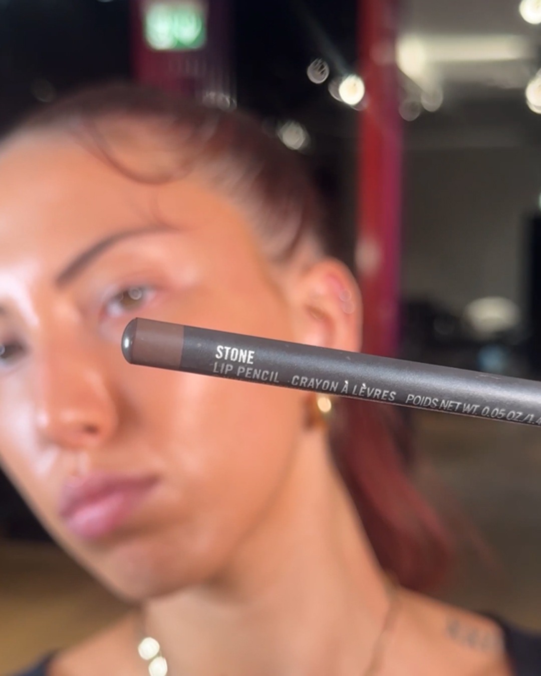 Een vrouw houdt een MAC Stone lippotlood vast, perfect om je lippen te definiëren en te accentueren.