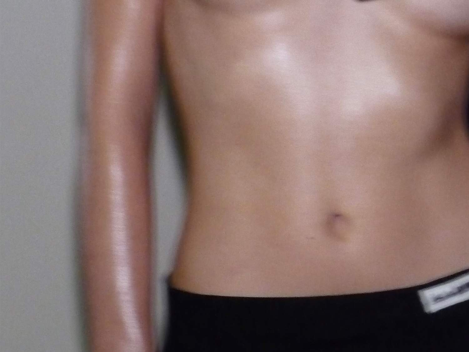 Close-up van een glanzende huid op een torso, met de nadruk op hydratatie en een gezonde uitstraling.