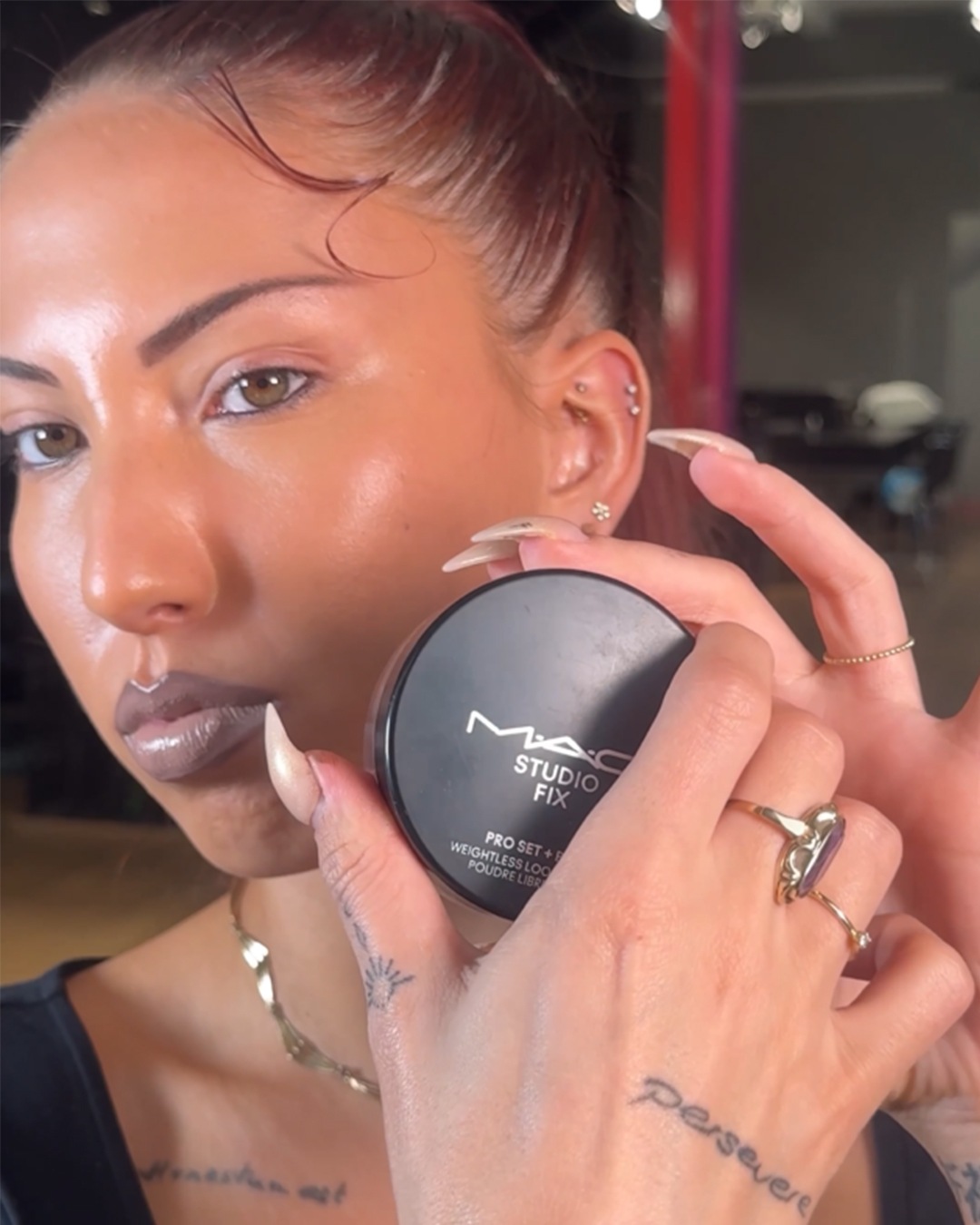 Een vrouw houdt een zwarte MAC Studio Fix poederdoos vast, perfect voor een gewichtloze finish.