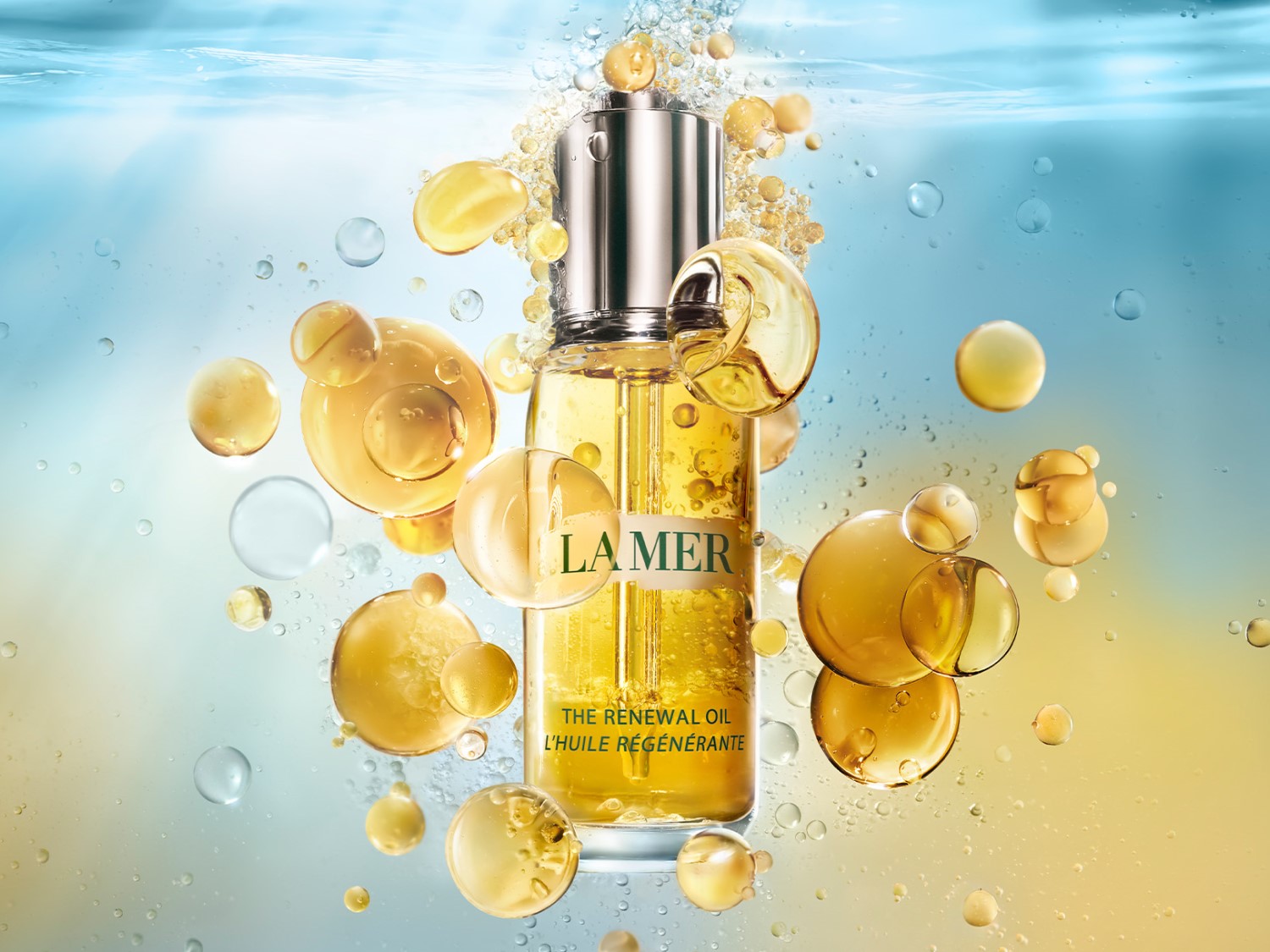 Buteleczka La Mer The Renewal Oil otoczona złotymi kroplami, prezentująca luksusowy olejek do pielęgnacji skóry.