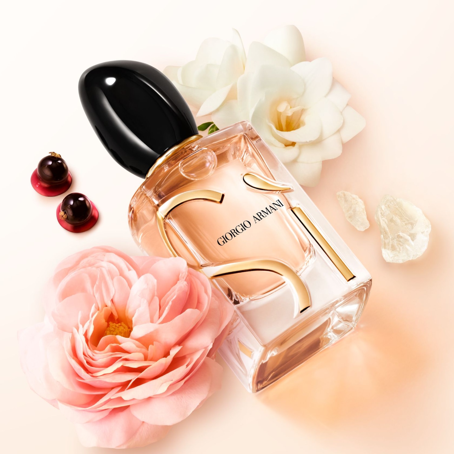 Een elegante Giorgio Armani parfumfles met zwarte dop, omringd door zachte roze en witte bloemen, en glinsterende kristallen.