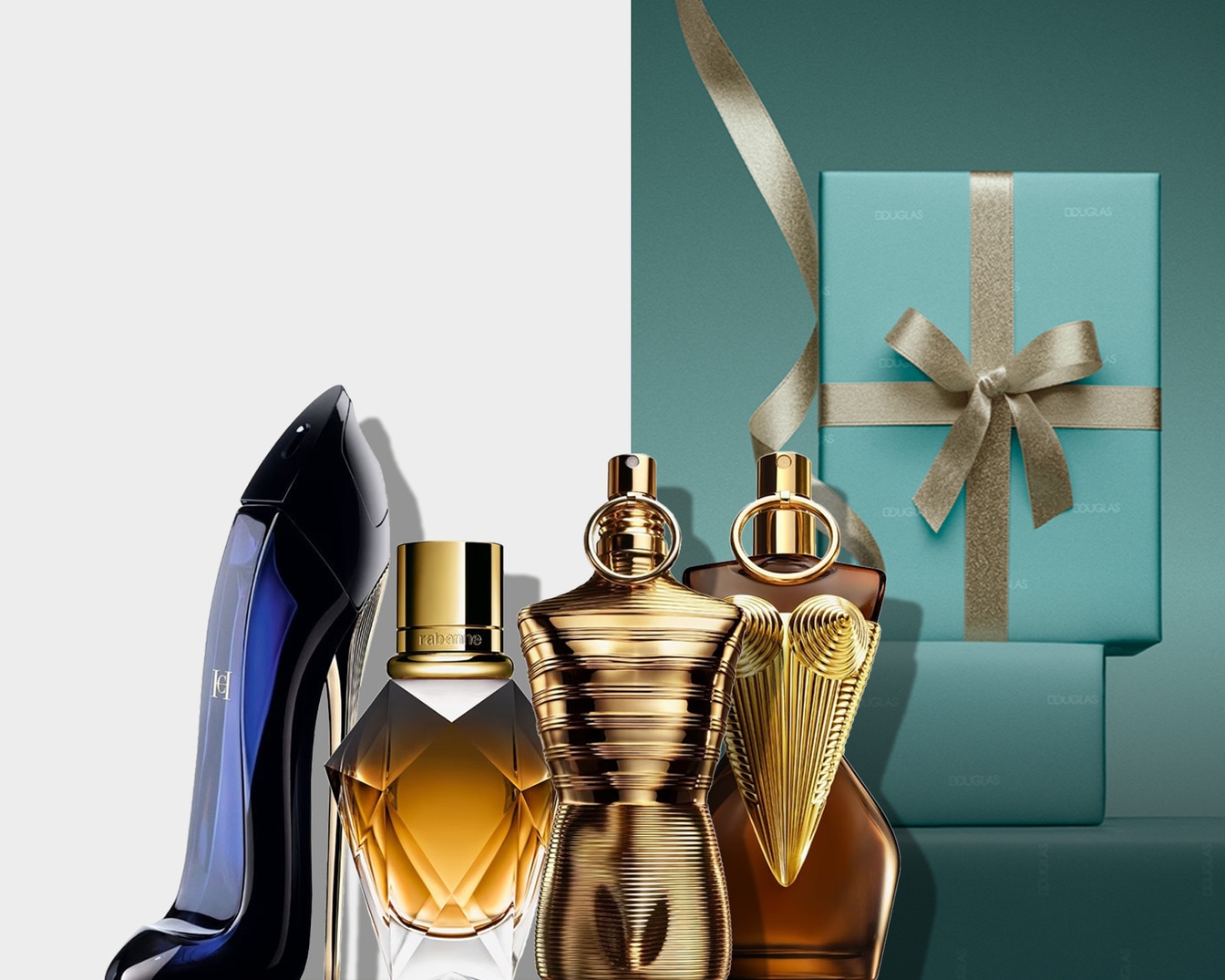 Elegantiškas kvepalų asortimentas su „Carolina Herrera Good Girl“ batelio formos buteliuku, „Rabanne“ deimanto formos buteliuku ir „Jean Paul Gaultier“ kūno formos buteliukais šalia mėlynos dovanų dėžutės su auksiniu kaspinu.