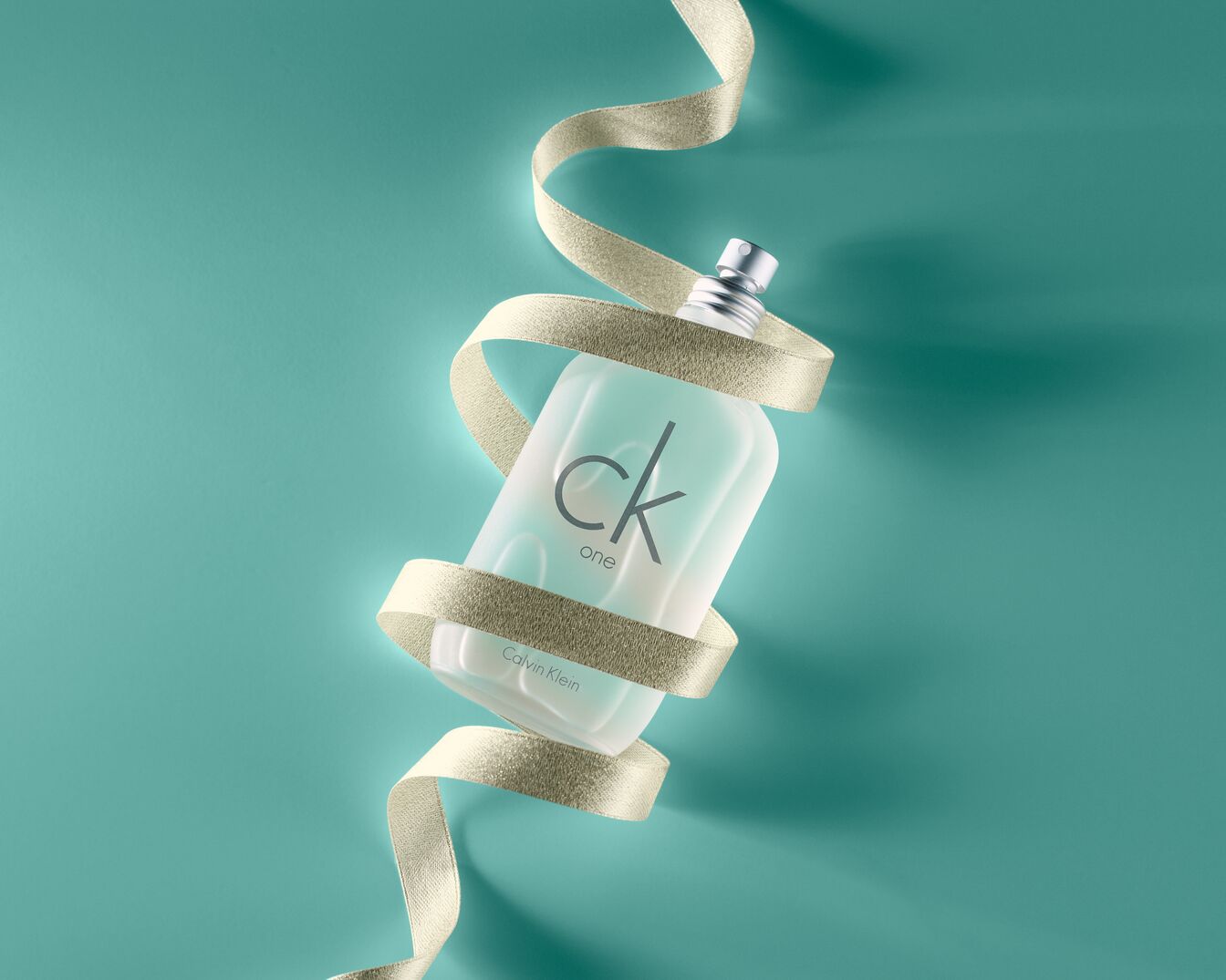 CK One by Calvin Klein buteliukas, apvyniotas auksine juostele ant turkio spalvos fono, suteikia elegancijos ir prabangos įspūdį.