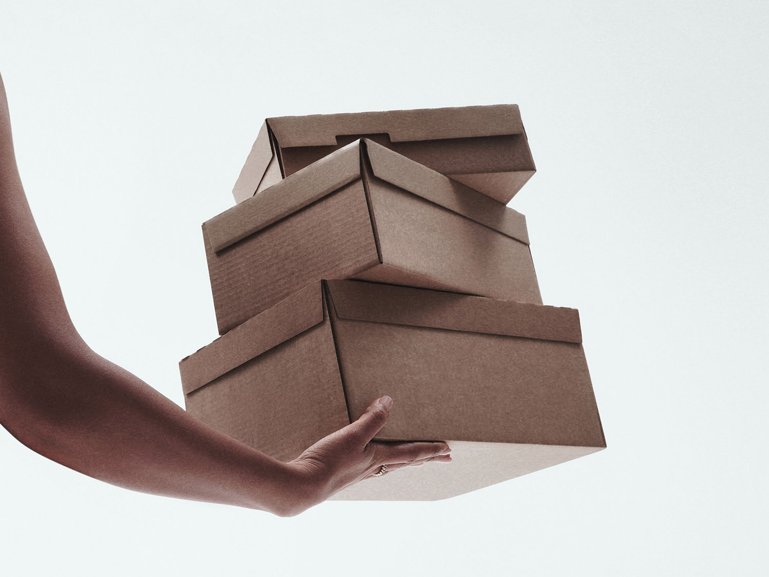 Une femme noire élégante, vêtue d'un ensemble noir deux pièces avec un haut bandeau et une jupe fendue, pose sur une plage au bord de l'océan.