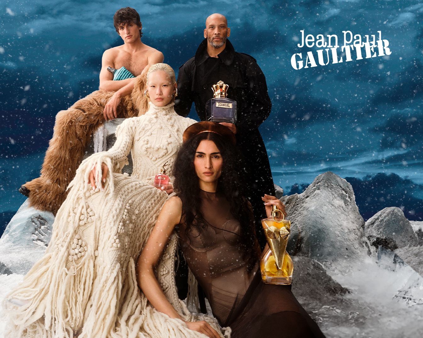En un paisaje invernal nevado, modelos diversos presentan fragancias de Jean Paul Gaultier, cada uno sosteniendo un frasco único, resaltando la elegancia y el atractivo de la marca.