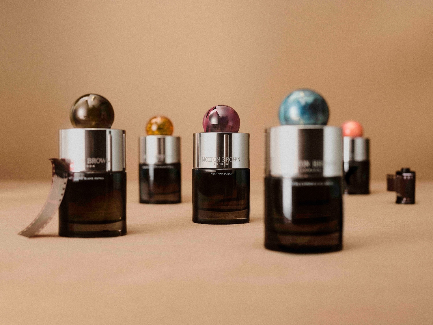 A Molton Brown London parfümök láthatók, mindegyik tetején színes golyóval, a címkék pedig a „Black Peppercorn”, a „Fiery Pink Pepper” és egy harmadik, kevésbé látható illatot mutatnak.