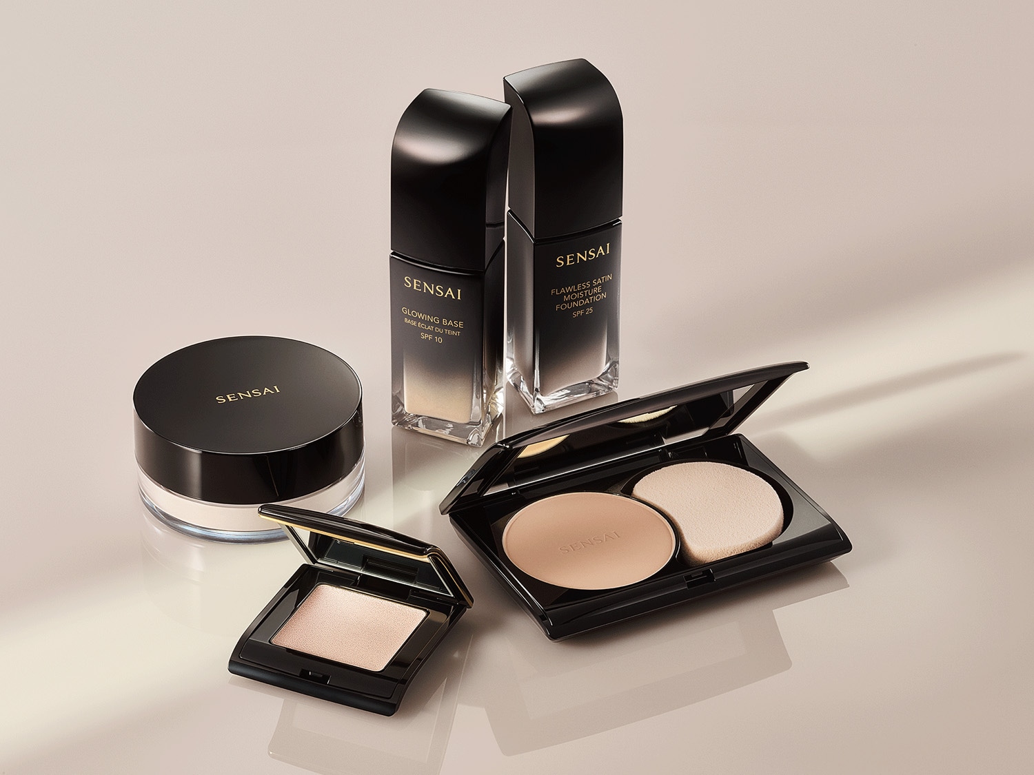 A Sensai sminktermékek kollekciója: ragyogó alapozó SPF 10-zel, hibátlan selyem hidratáló alapozó SPF 25-tel, púder és kompakt púder fekete csomagolásban.