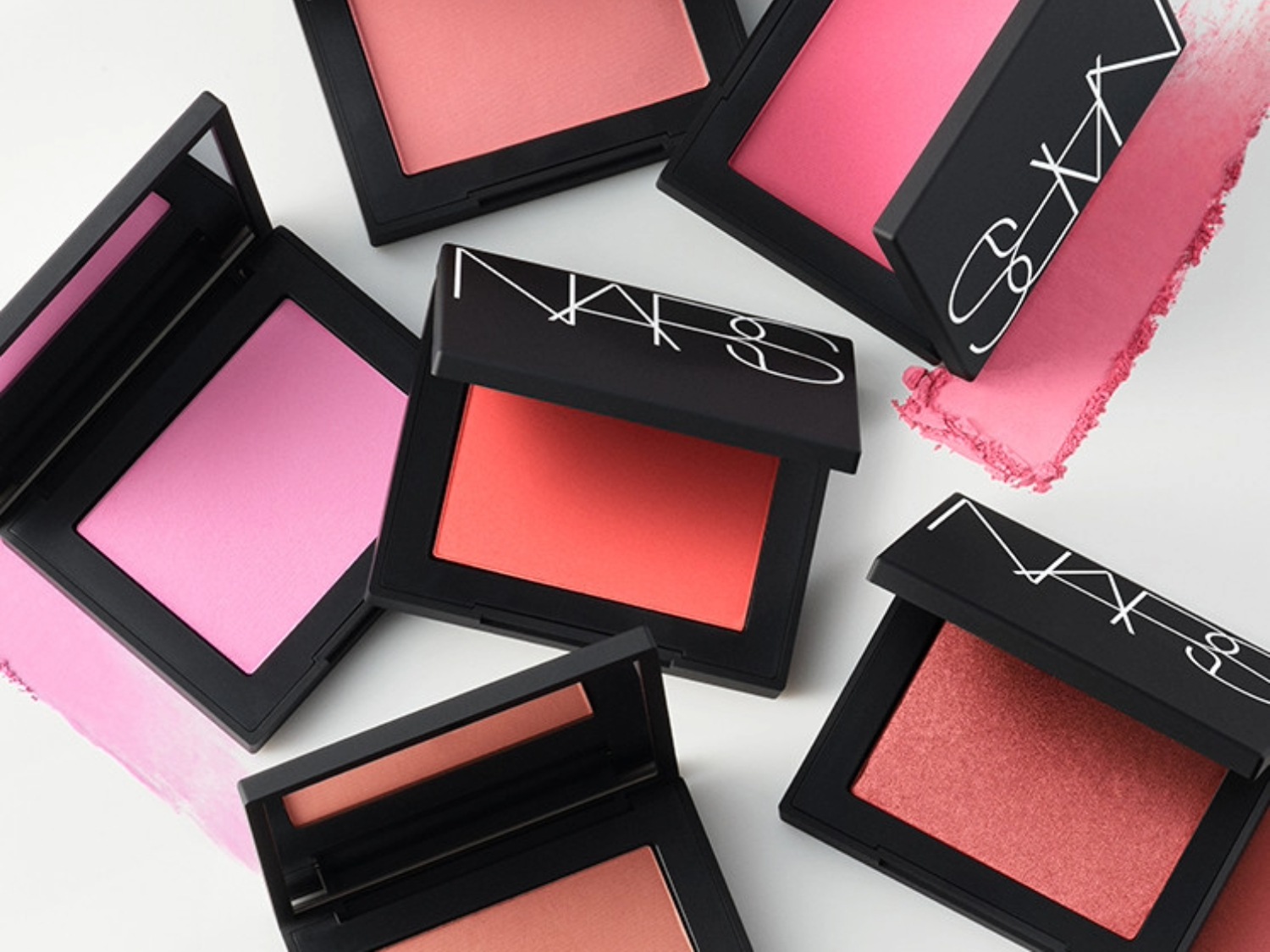 Verschillende tinten NARS blushers in zwarte compacte doosjes, variërend van zachtroze tot koraal, voor een frisse en stralende blos.