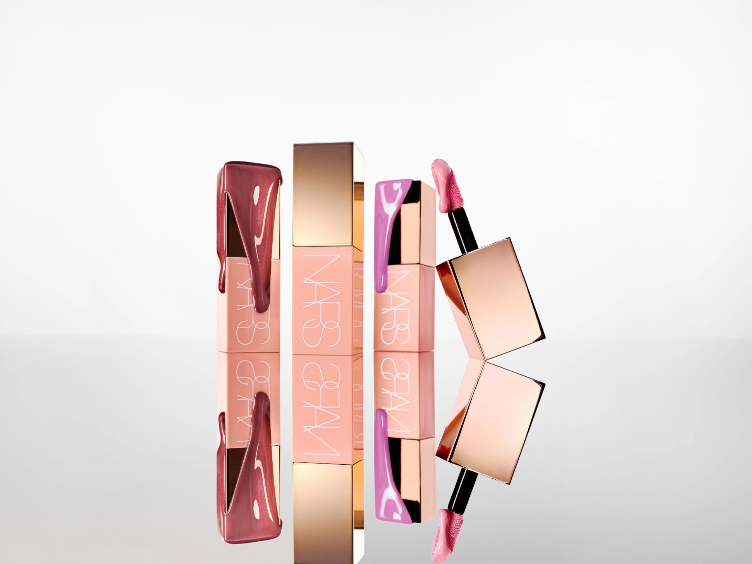 NARS lipgloss in roze en paarse tinten met een glanzende gouden dop, perfect voor een glamoureuze look.