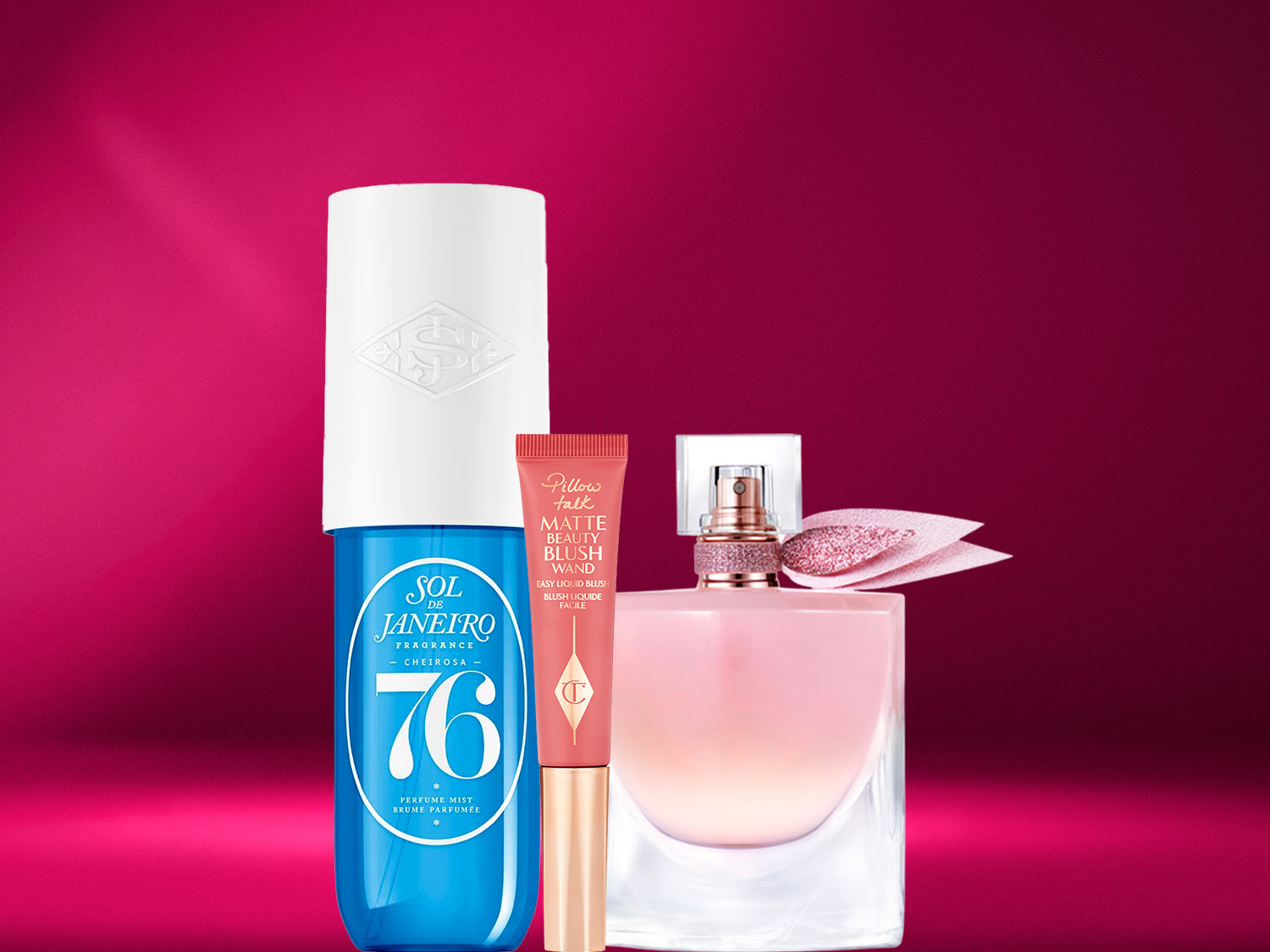 Šis vaizdas pristato „Sol de Janeiro Cheirosa '76“ purškiklį, „Pillow Talk“ matinį skaistalų pieštuką ir rožinį „Lancôme“ kvepalų buteliuką ant rausvai raudono fono.