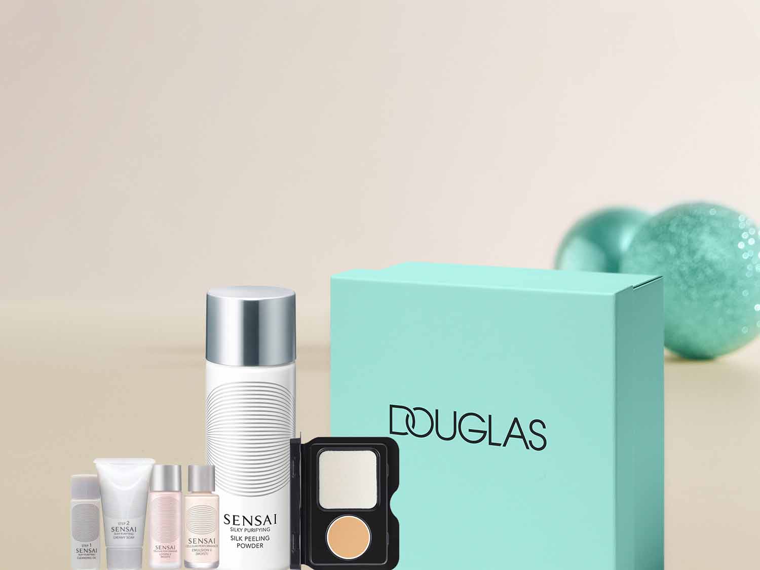 Zestaw kosmetyków Sensai do pielęgnacji twarzy, w skład którego wchodzą puder peelingujący, emulsja i krem w białych i różowych opakowaniach, obok turkusowego pudełka Douglas.