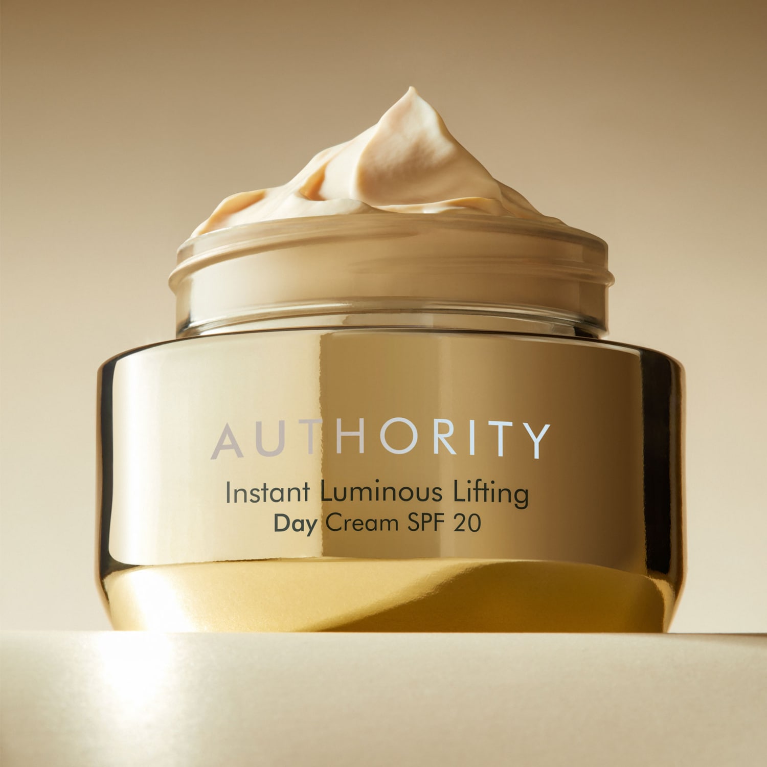Złoty słoik kremu Authority Instant Luminous Lifting Day Cream SPF 20 z beżową zawartością, zapewniający natychmiastowy efekt liftingu i ochronę przeciwsłoneczną.