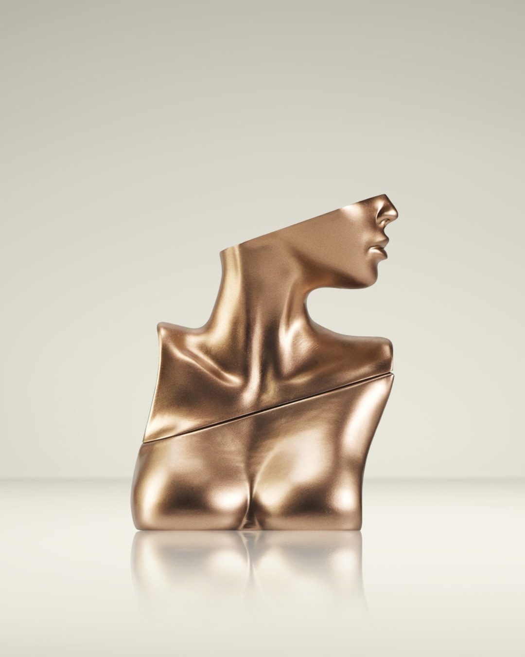 Een bronzen parfumflesje in de vorm van een vrouwelijk torso, met een schuine snede die de hals en borst scheidt, staat op een glanzend oppervlak.