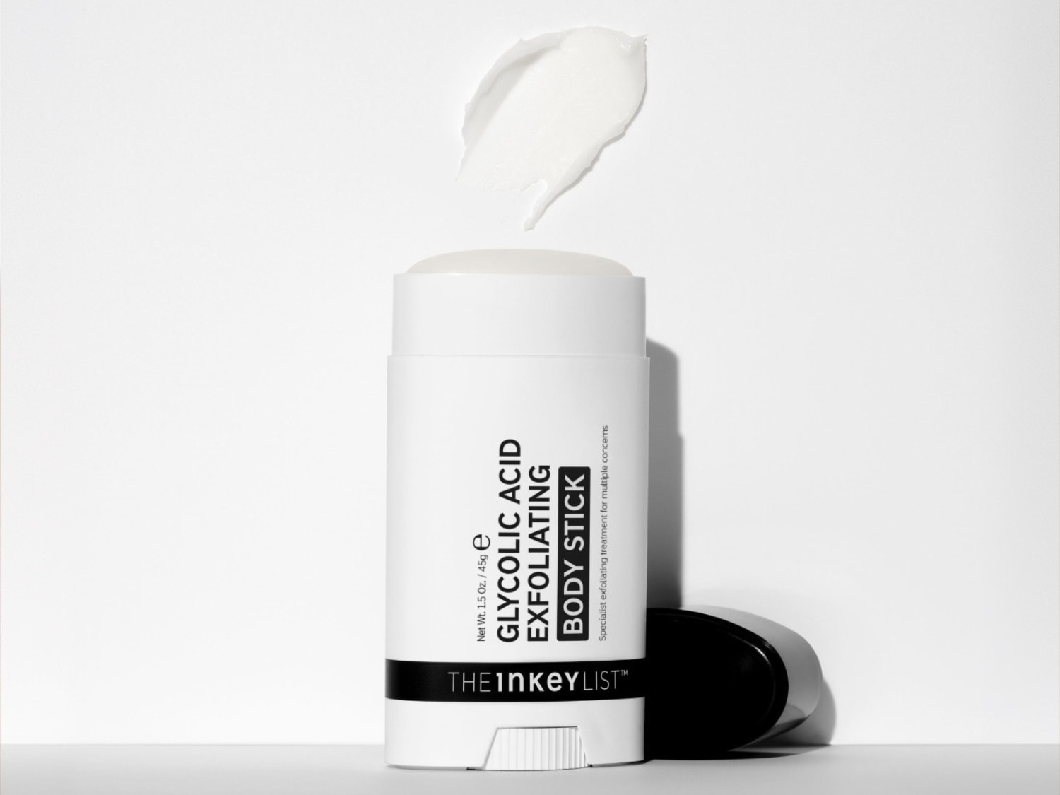 De Inkey List Glycolic Acid Exfoliating Body Stick, een witte stick met zwarte tekst, is een specialistische exfoliërende behandeling voor diverse huidproblemen, met een veeg van de witte crème erboven.