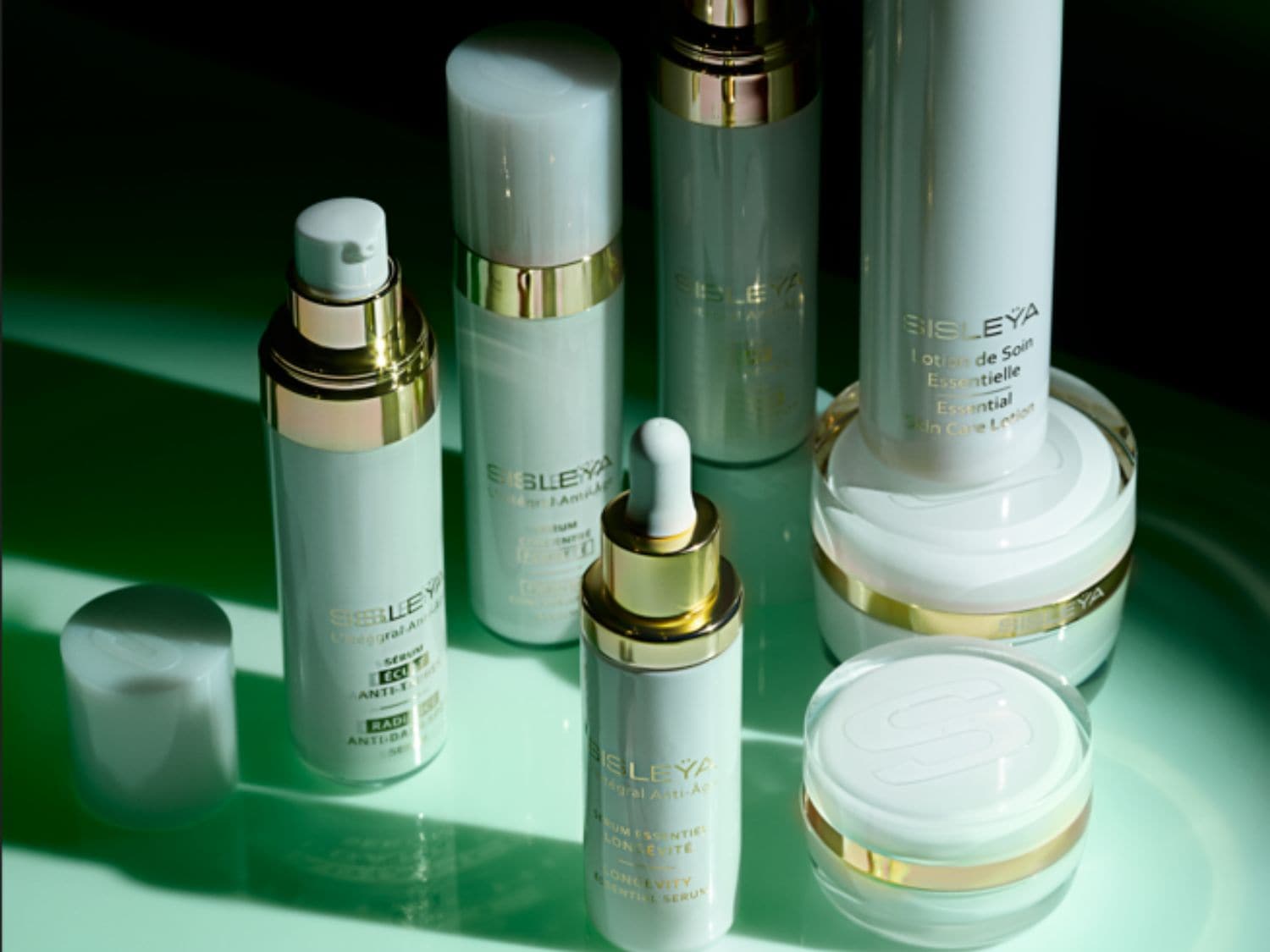Ontdek Sisley's collectie van huidverzorgingsproducten, verpakt in elegante witte flessen met gouden accenten, voor een complete anti-aging routine.