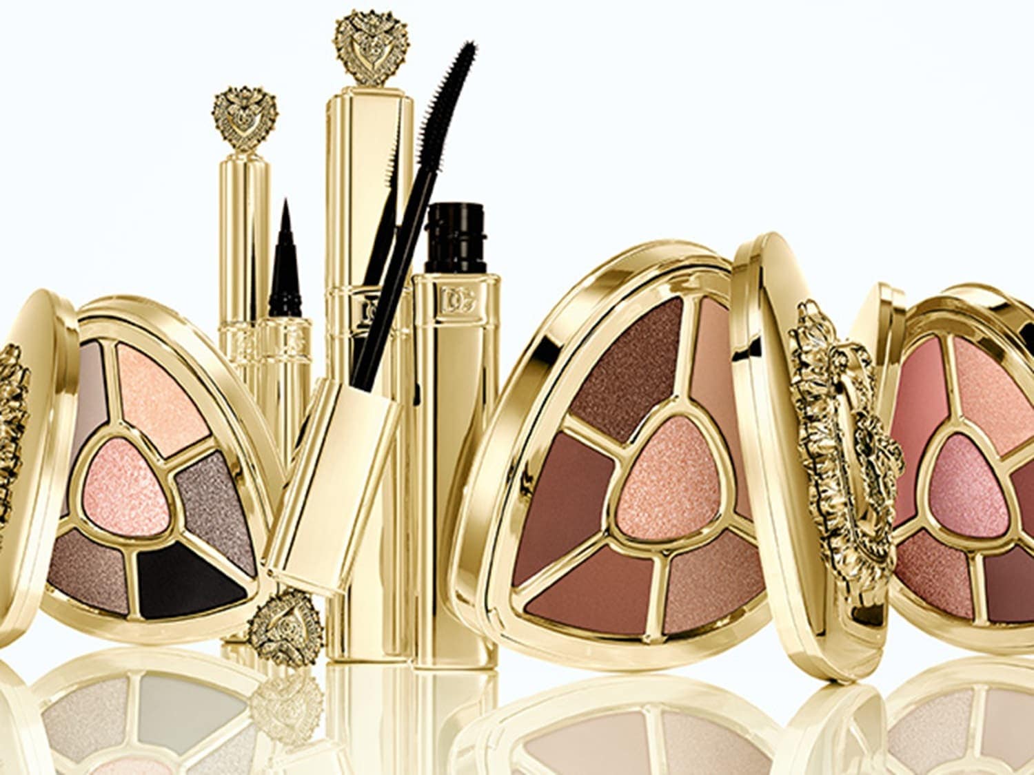 Gouden make-upcollectie met oogschaduwpaletten in verschillende kleuren, mascara en eyeliner voor een complete look.