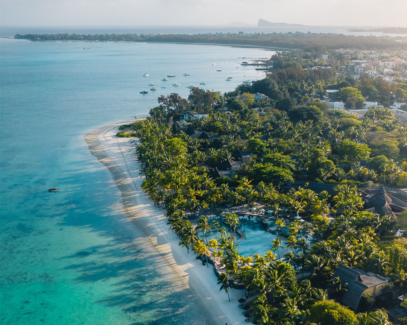 Vista aerea mozzafiato di una spiaggia tropicale con acque turchesi, palme ondeggianti e sabbia bianca incontaminata, che invita al relax e alla scoperta.