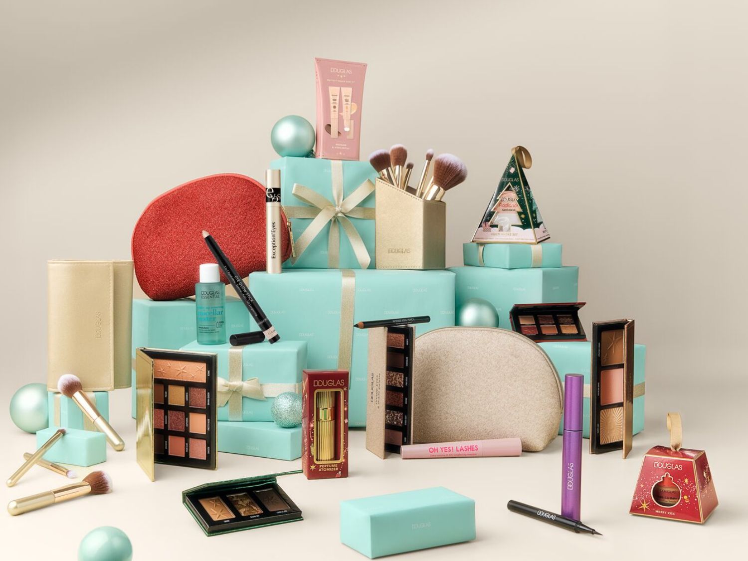 Představujeme kosmetické produkty Douglas, včetně očních stínů, štětců a balíčků péče o pleť, vše úhledně uspořádané na modrých dárkových krabičkách.