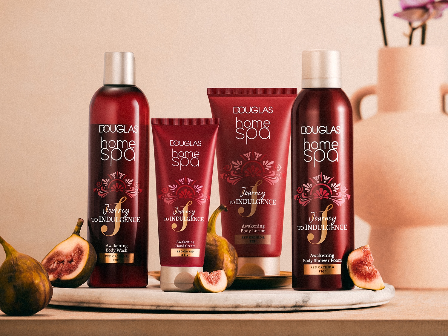 Vier roodkleurige Douglas Home Spa producten, waaronder body wash, handcrème, bodylotion en douchefoam, verrijkt met rode orchidee en vijg.