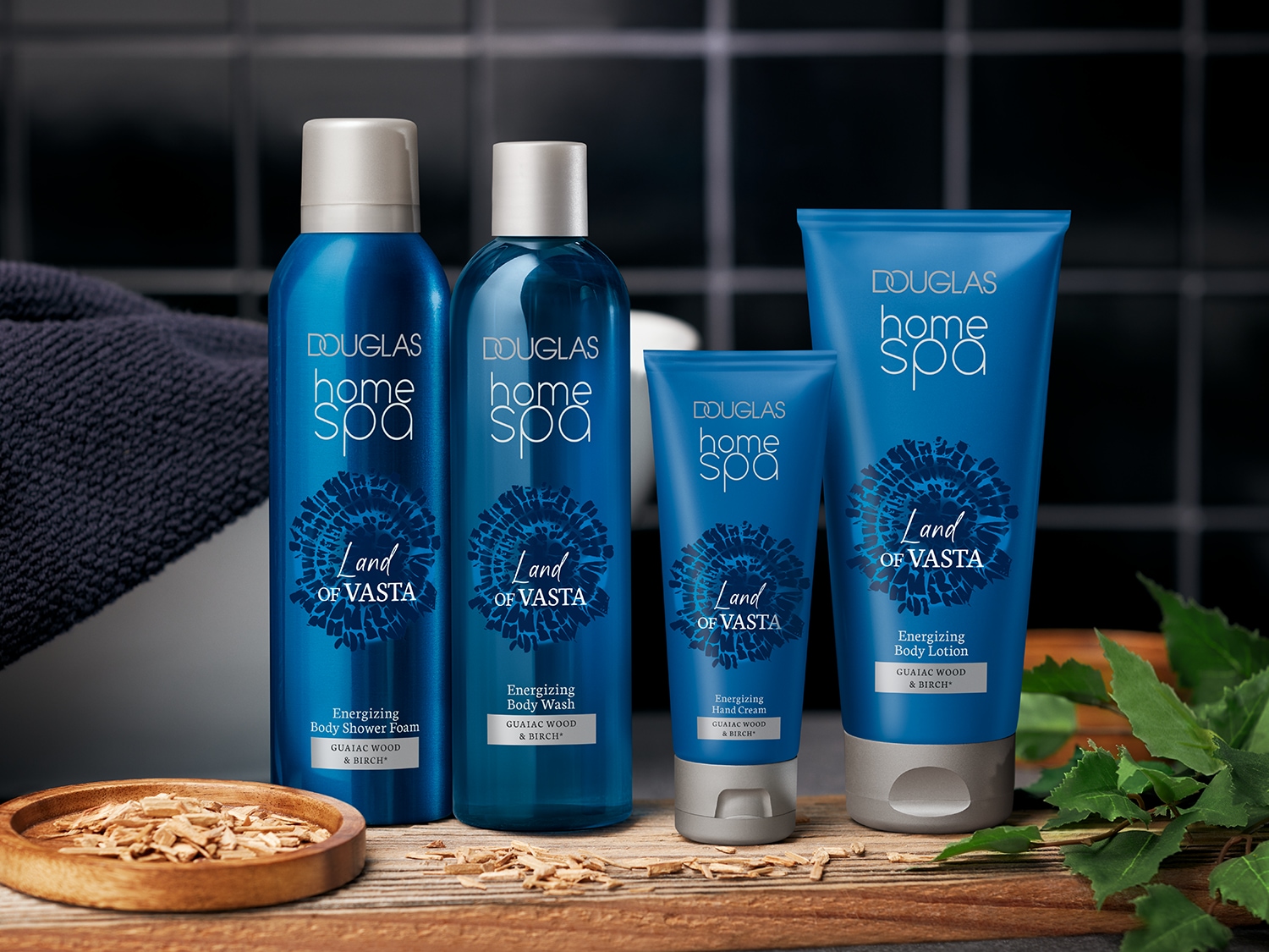 Vier blauwe Douglas Home Spa-producten uit de Land of Vasta-lijn, waaronder body wash, shower foam, handcrème en bodylotion, verrijkt met guaiac hout en berk.