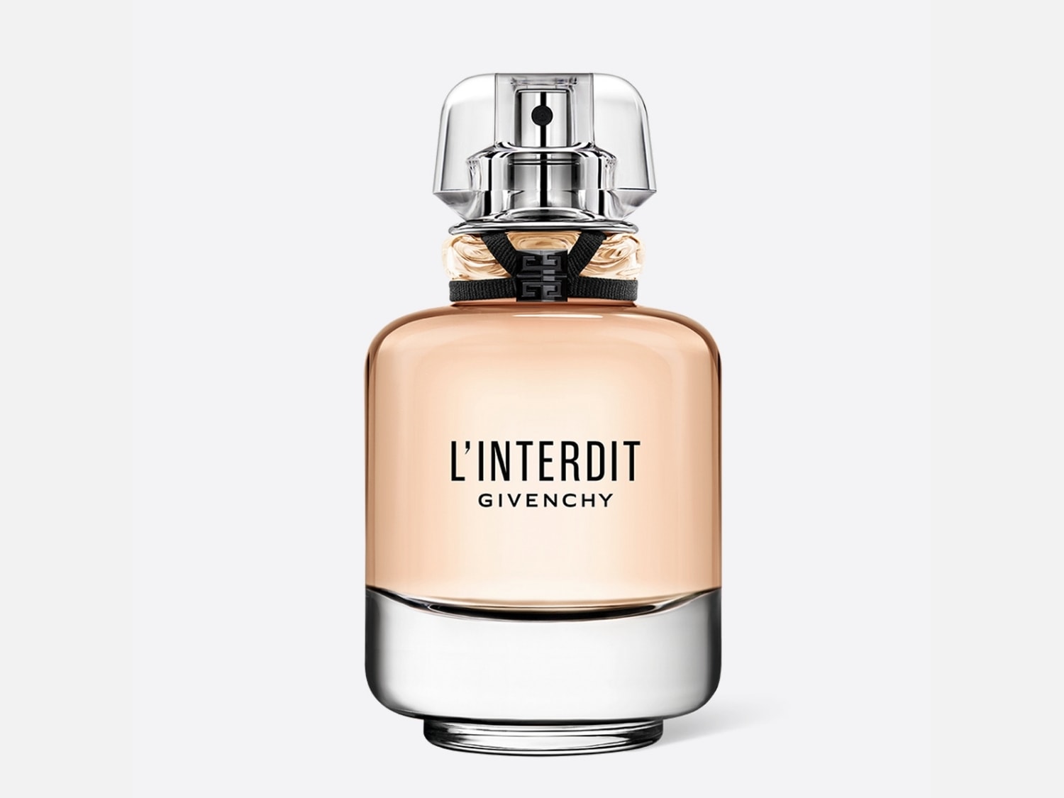 El frasco de perfume L'Interdit de Givenchy presenta un diseño elegante con un cuerpo de vidrio color melocotón y una base plateada, coronado con un tapón transparente y detalles en negro.