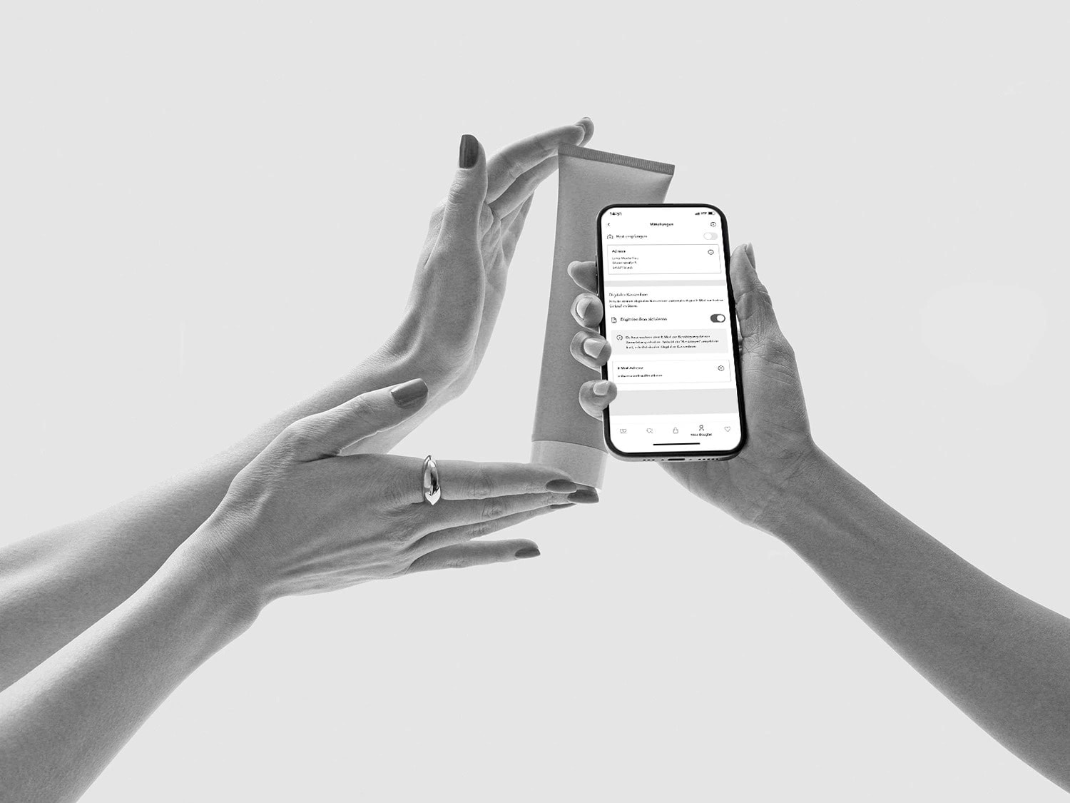 Gros plan sur les mains tenant un tube de crème et un smartphone affichant les paramètres de l'application, le tout en noir et blanc.