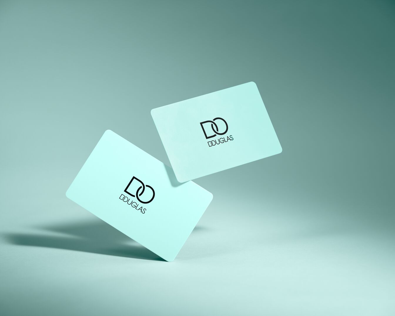 Zwei hellblaue Karten mit dem Douglas-Logo in Schwarz, schwebend vor einem passenden Hintergrund.