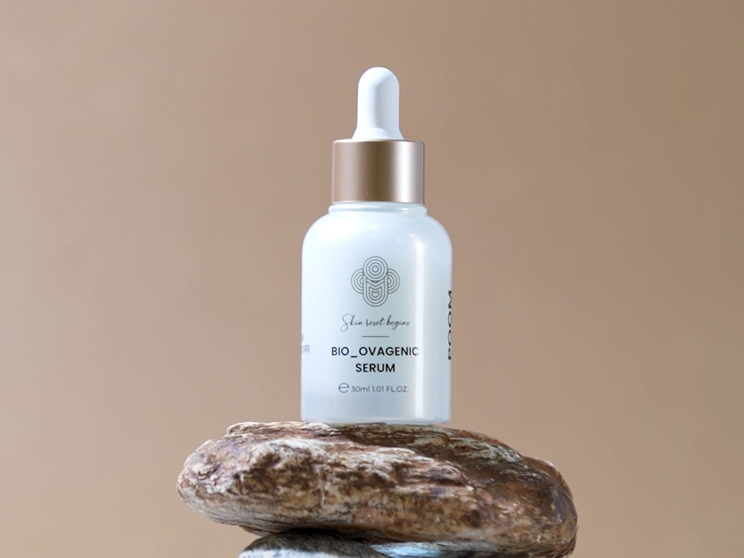 El suero Bio-Ovagenic viene en un frasco blanco con un gotero blanco y dorado, colocado sobre una piedra marrón.