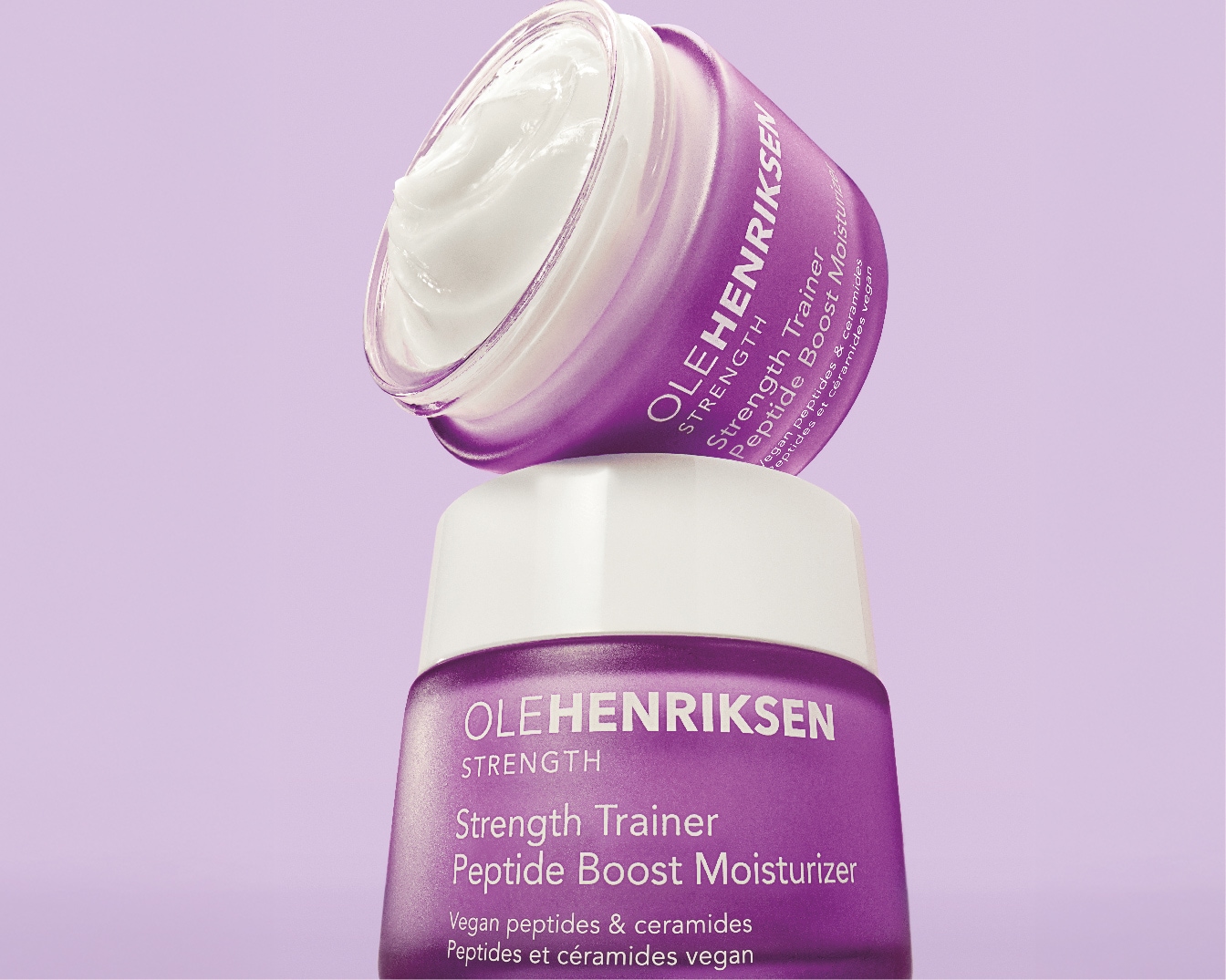 De Olehenriksen Strength Trainer Peptide Boost Moisturizer in een paarse verpakking met een witte deksel, belooft een veganistische formule met peptiden en ceramiden voor een gehydrateerde en sterke huid.