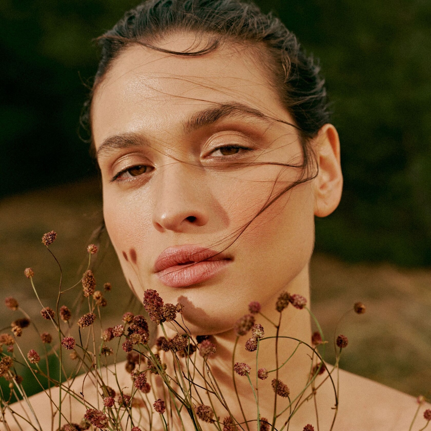 Portrait d'une femme avec un maquillage naturel et des fleurs séchées, capturant une beauté douce et authentique.