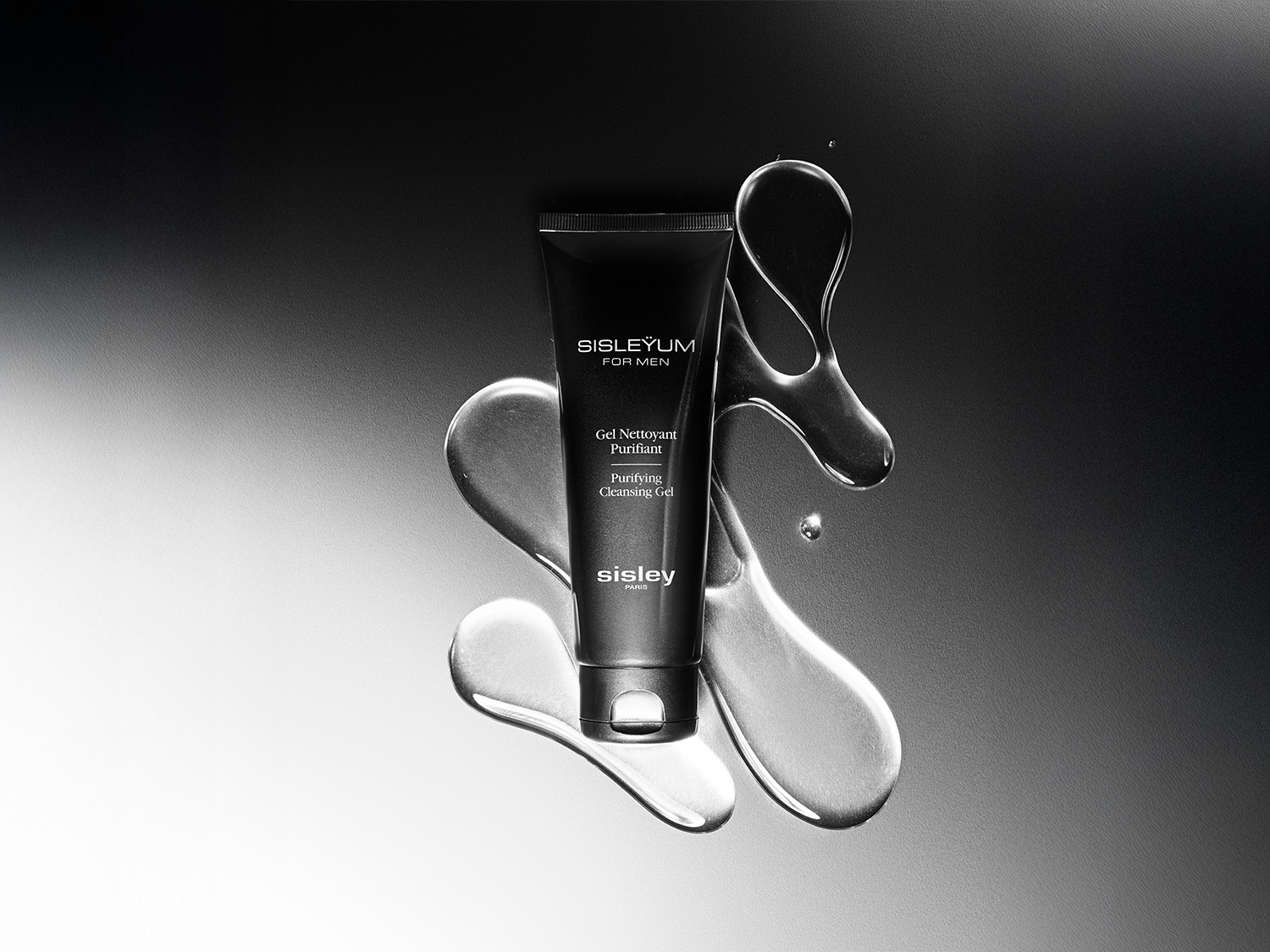 Czarna tuba Sisleyum For Men Gel Nettoyant Purifiant otoczona kroplami wody na szarym tle, oferująca głębokie oczyszczenie skóry.