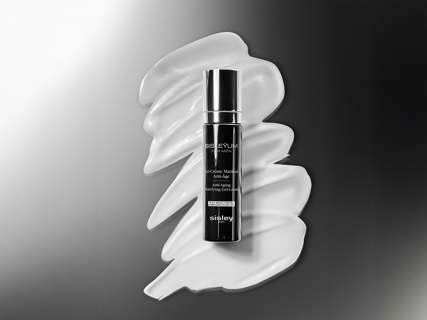 Czarna butelka Sisleyum For Men Gel-Crème Matifiant Anti-Age Anti-Aging Mattifying Gel-Cream leży na białym kremie, zapewniając pielęgnację przeciwstarzeniową dla mężczyzn.