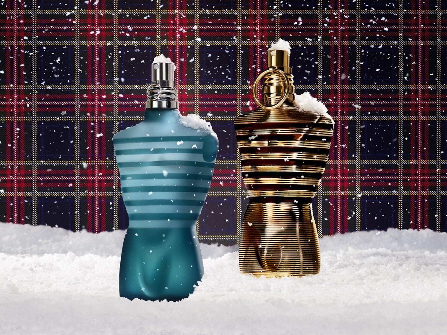 Twee torso-vormige parfumflessen, een blauwe met witte strepen en een gouden, staan in de sneeuw tegen een Schotse ruit achtergrond.