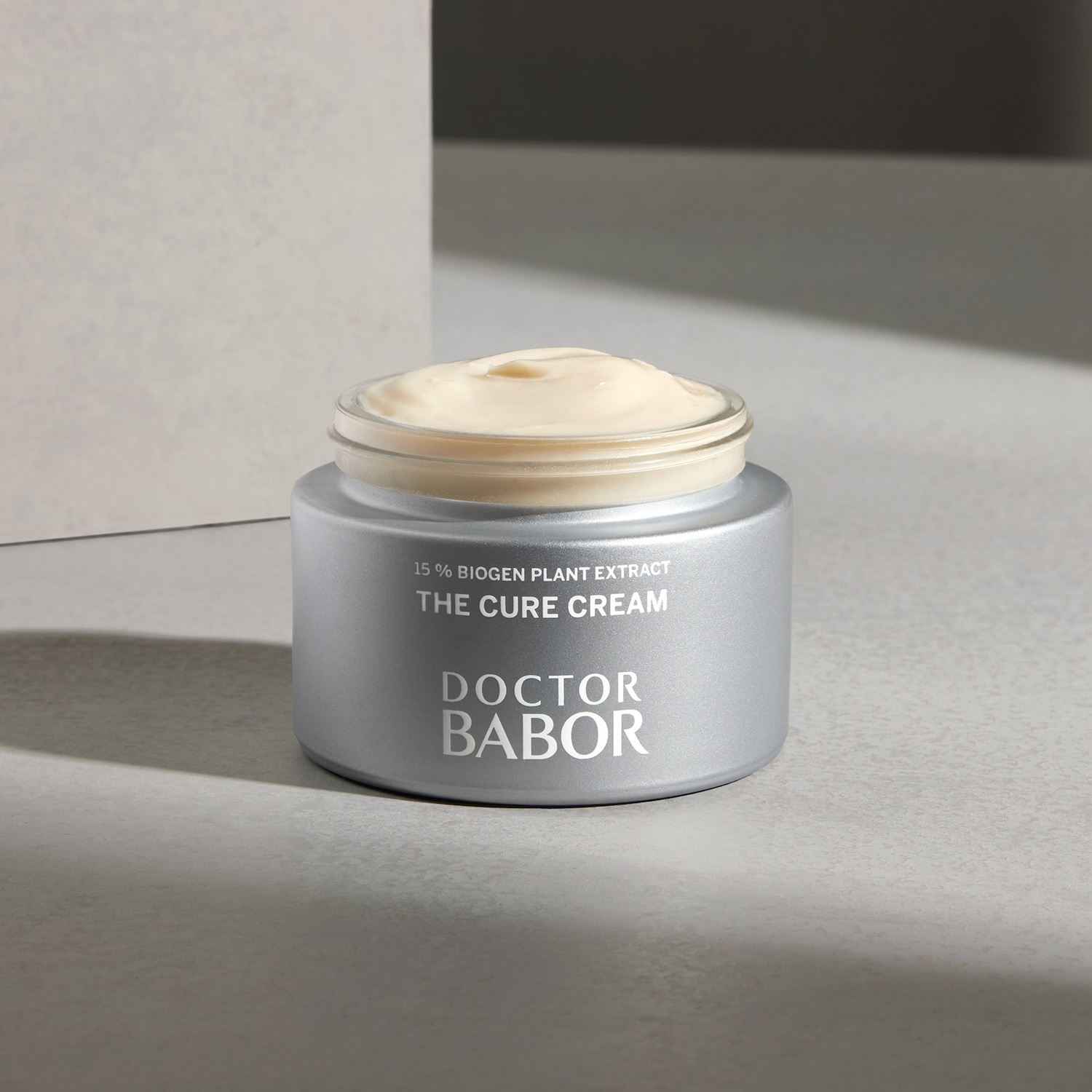 Nahaufnahme von Doctor Babor The Cure Cream mit 15% Biogen Pflanzenextrakt in einer silbernen Dose mit einer Schicht hellgelber Creme.