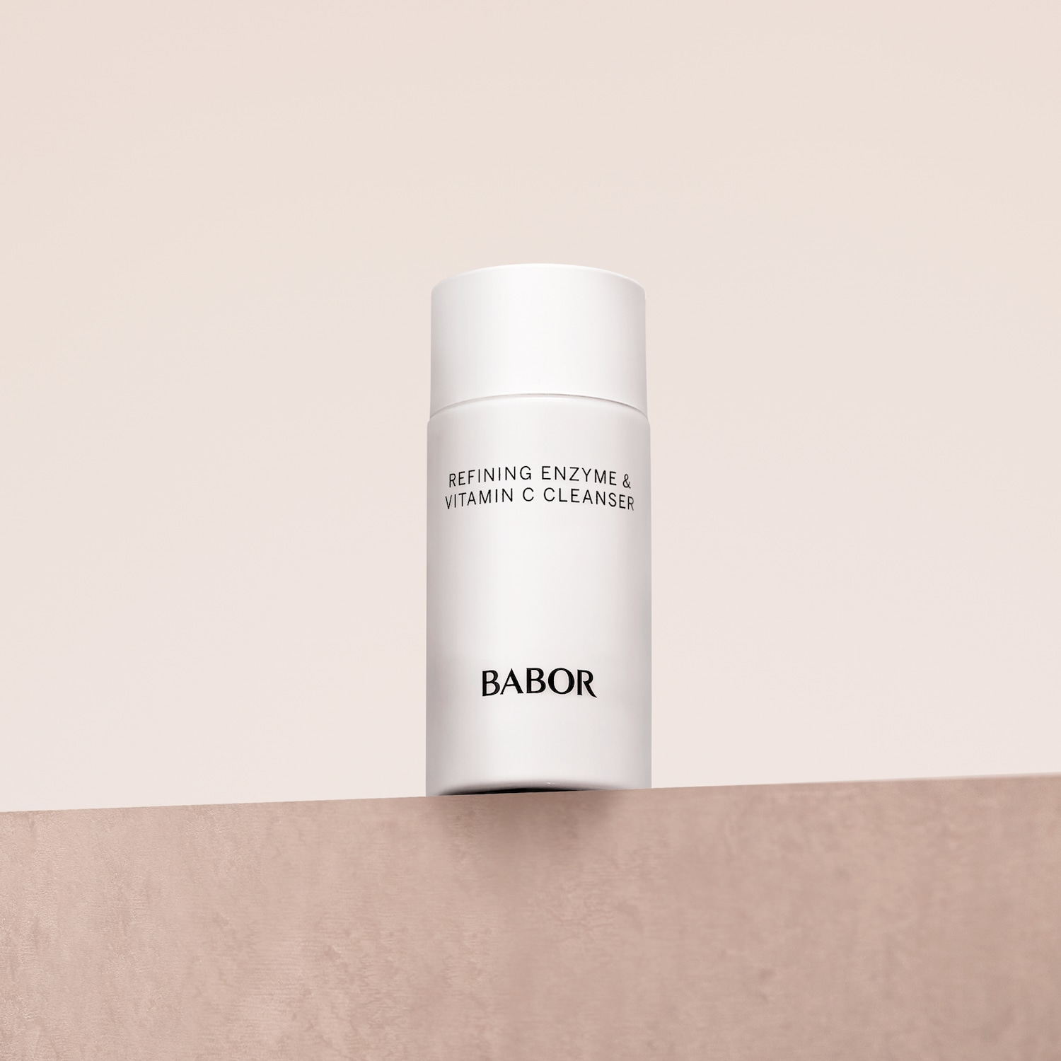 Die weiße Flasche Babor Refining Enzyme & Vitamin C Cleanser steht auf einer beigen Oberfläche.