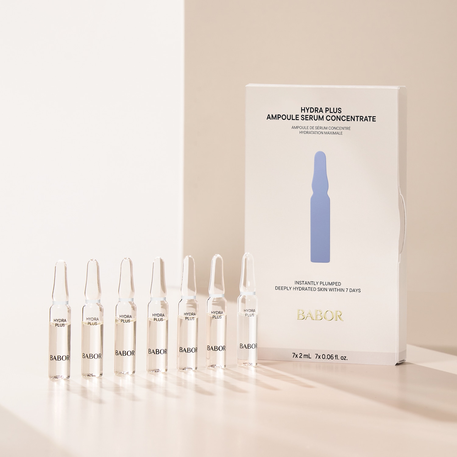 Sieben durchsichtige Babor Hydra Plus Ampullen stehen neben einer weißen Packung, die ein blaues Ampullenbild und den Text 'Sofort pralle, tiefenhydrierte Haut in 7 Tagen' zeigt.
