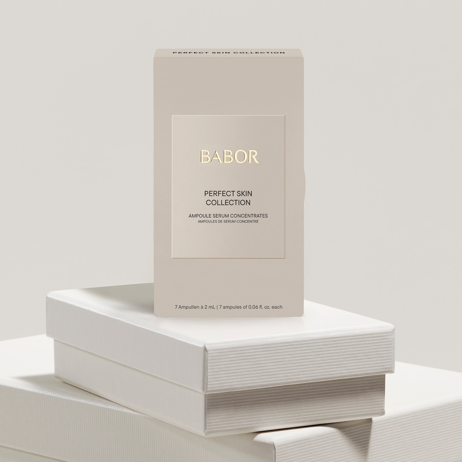 Die Babor Perfect Skin Collection präsentiert Ampullen-Serum-Konzentrate in einer eleganten, hellbraunen Verpackung mit goldenen Akzenten, die auf einem gestuften weißen Podest steht.